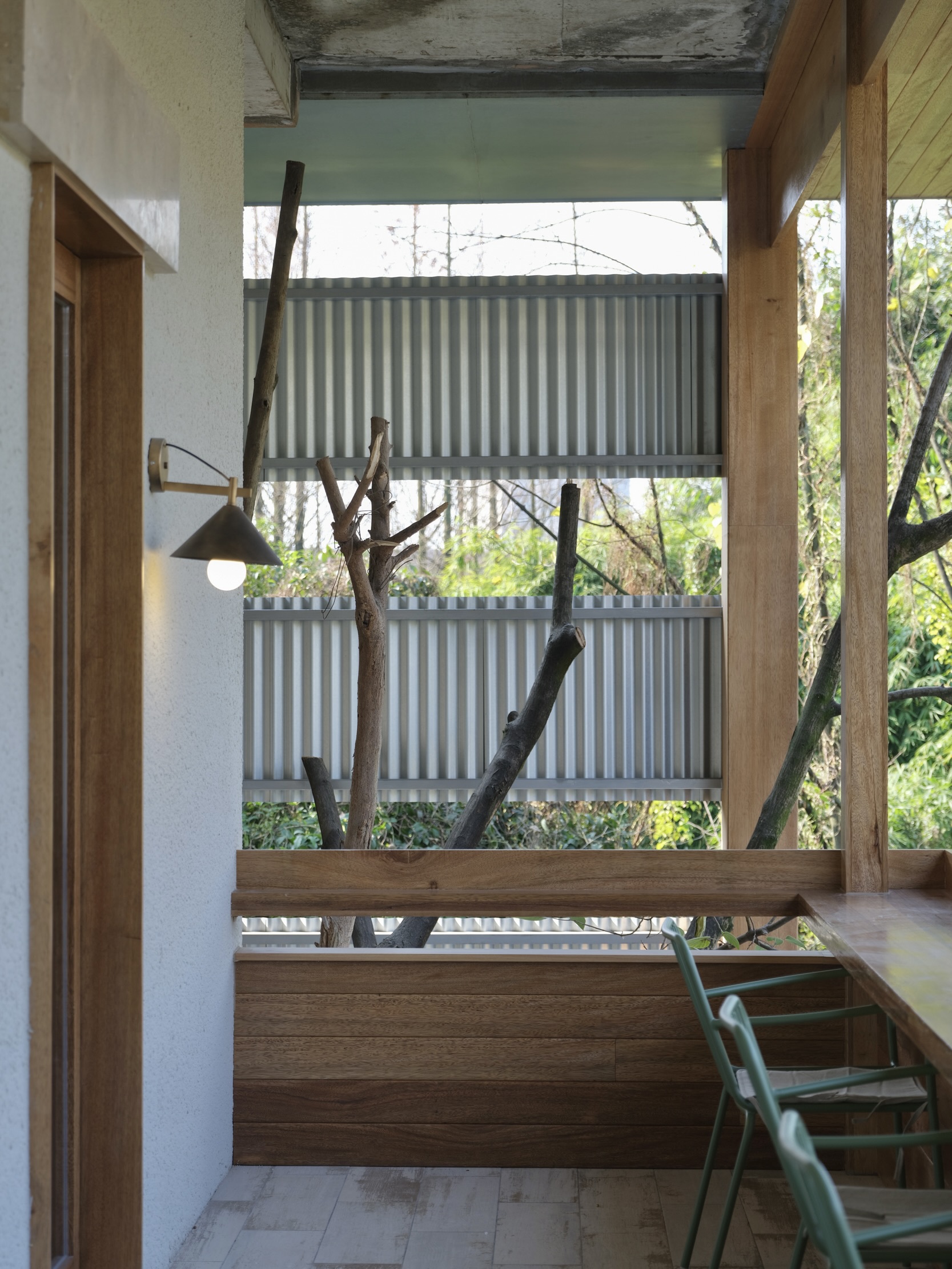 Interior stairwell with timber treads and a view to corrugated screens and tree branches outside