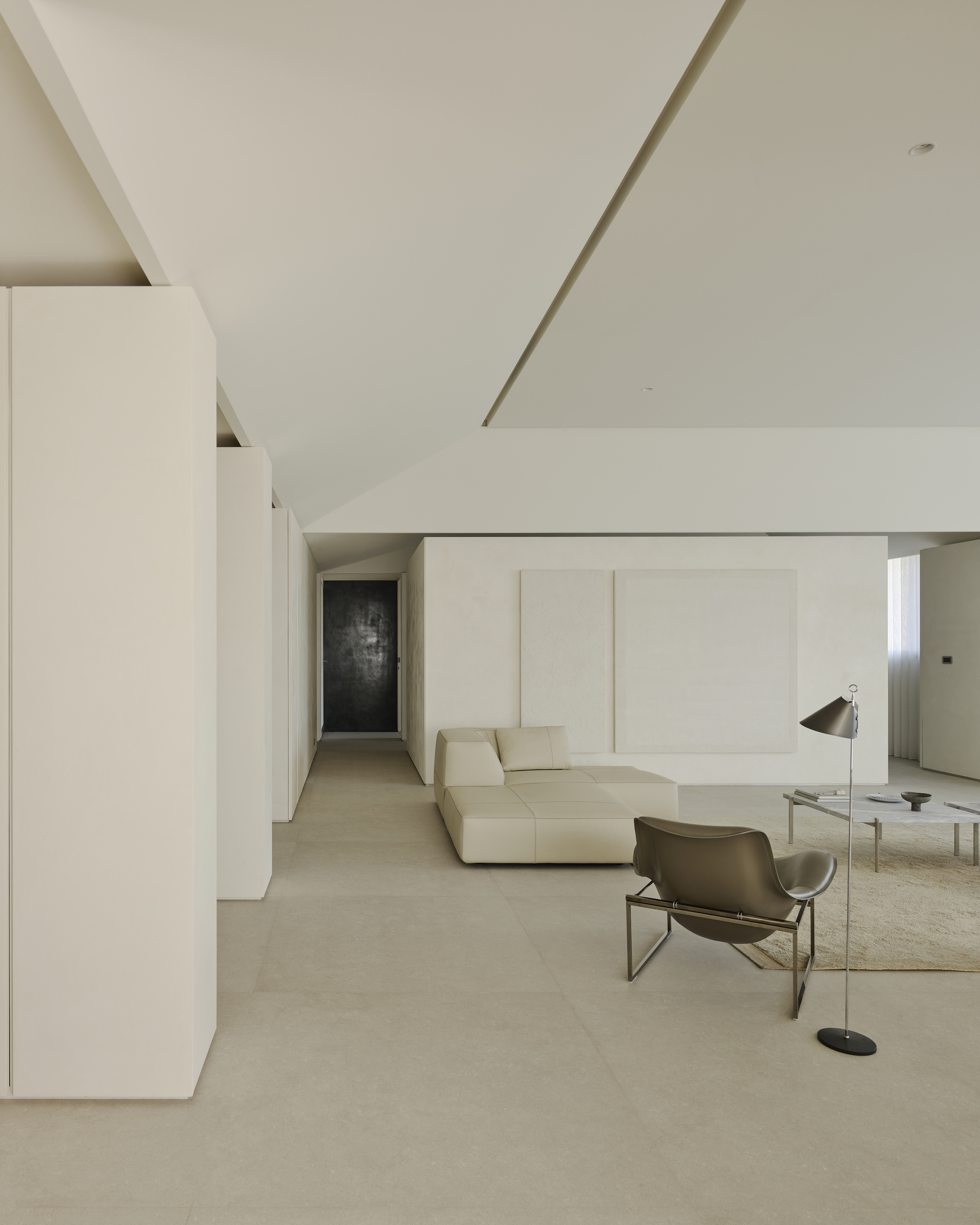 Living area with recessed lighting channel in the ceiling and dark panel visible in hallway distance