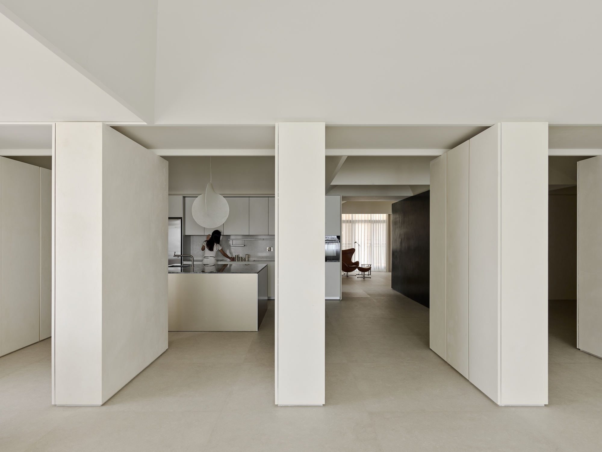 Repeating white columns dividing interior spaces with kitchen and seating areas glimpsed through openings