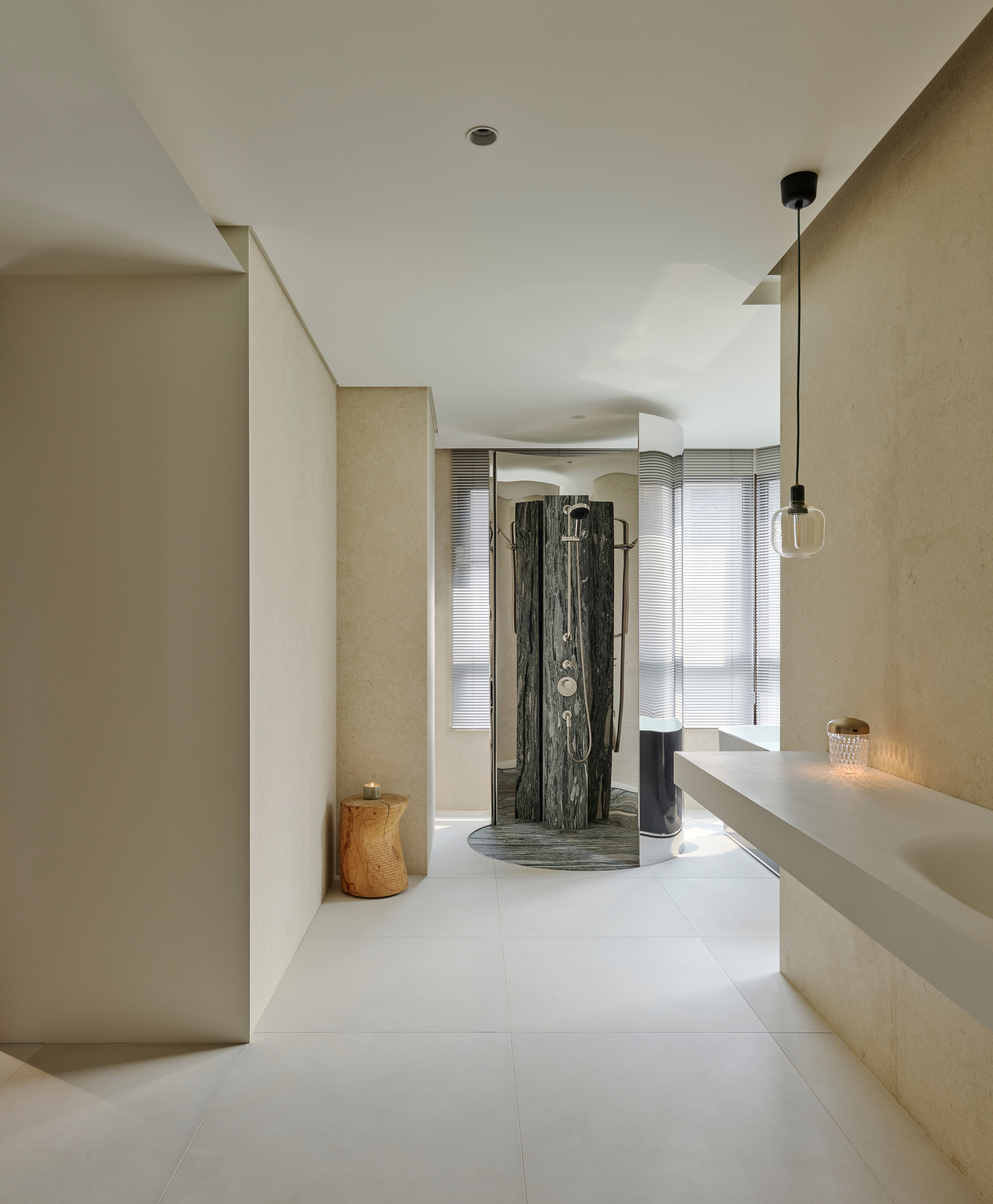 Bathroom with cylindrical dark stone shower enclosure beneath curved ceiling and pendant lighting