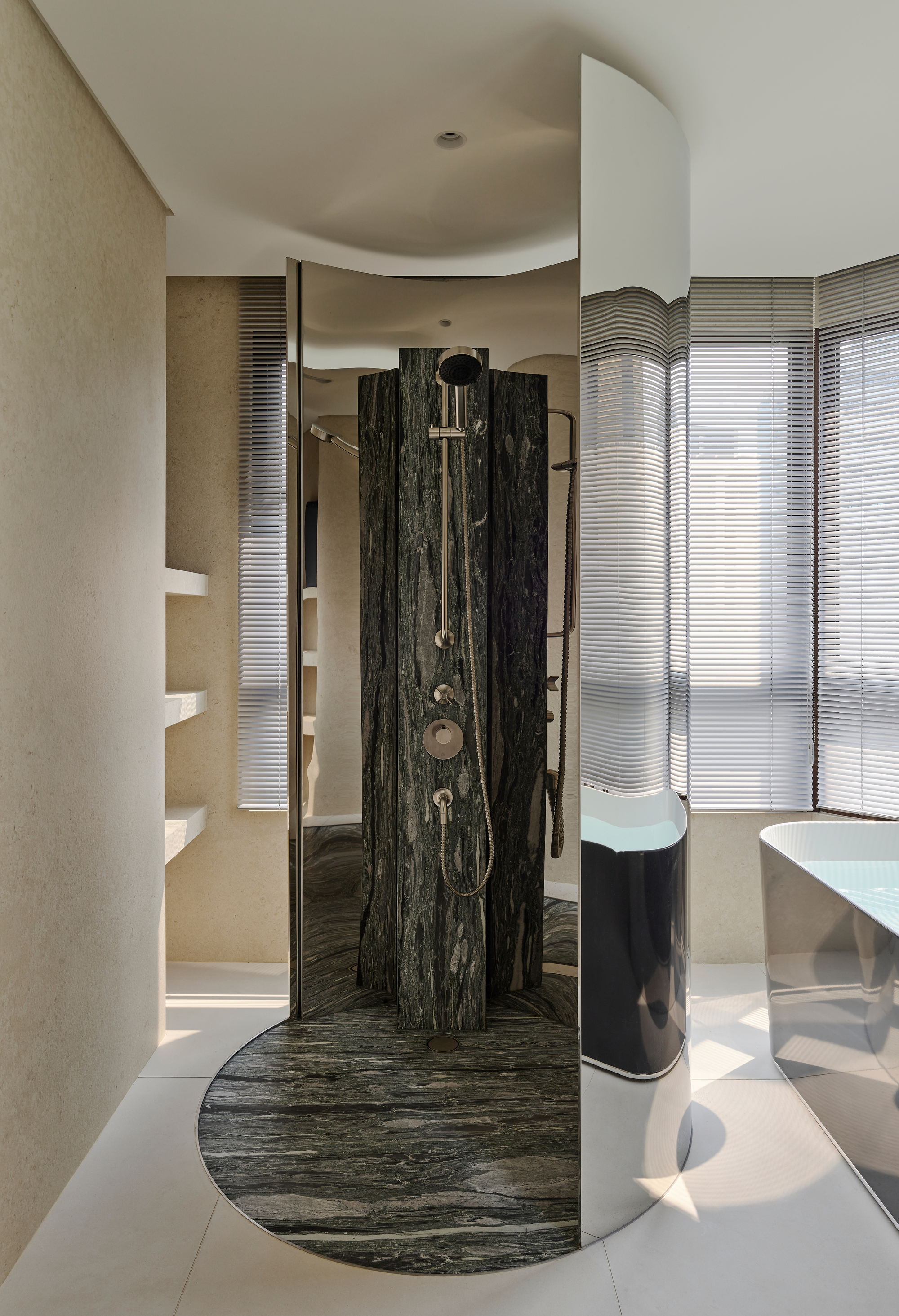 Freestanding shower with veined black marble surround and curved base beneath fluted glass windows