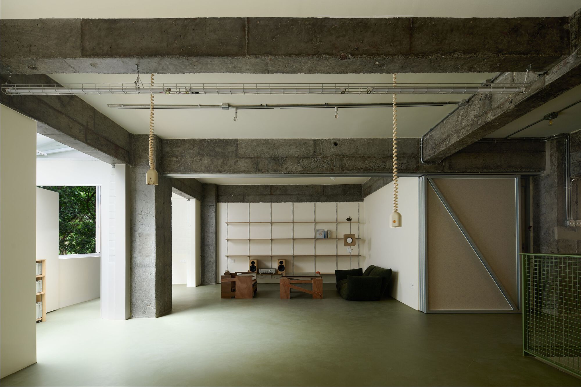Open concrete-framed interior with rope-wrapped pendant lights and a translucent sliding partition at one end