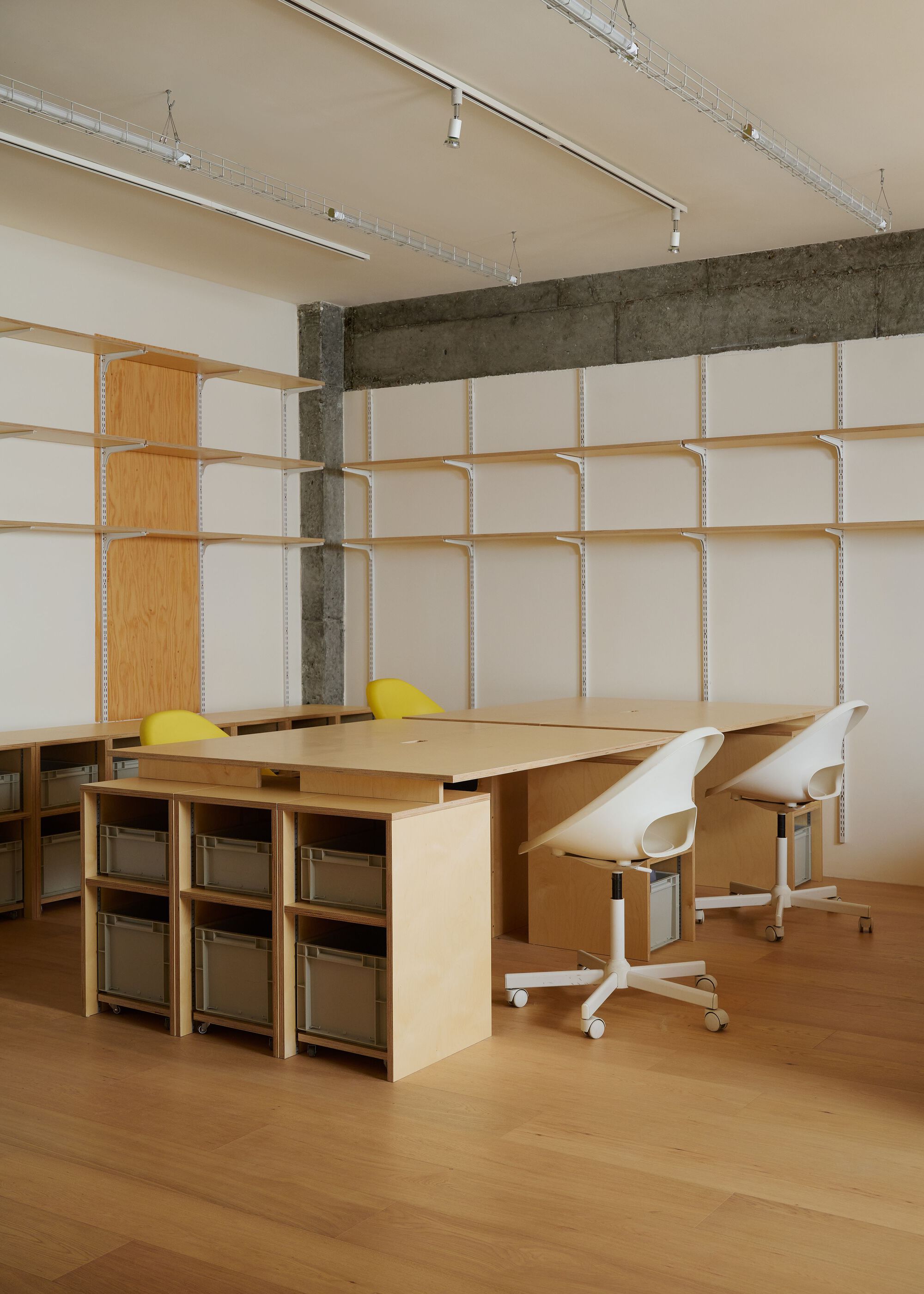 Plywood desk with integrated storage cubes and office chairs against a modular fabric panel wall