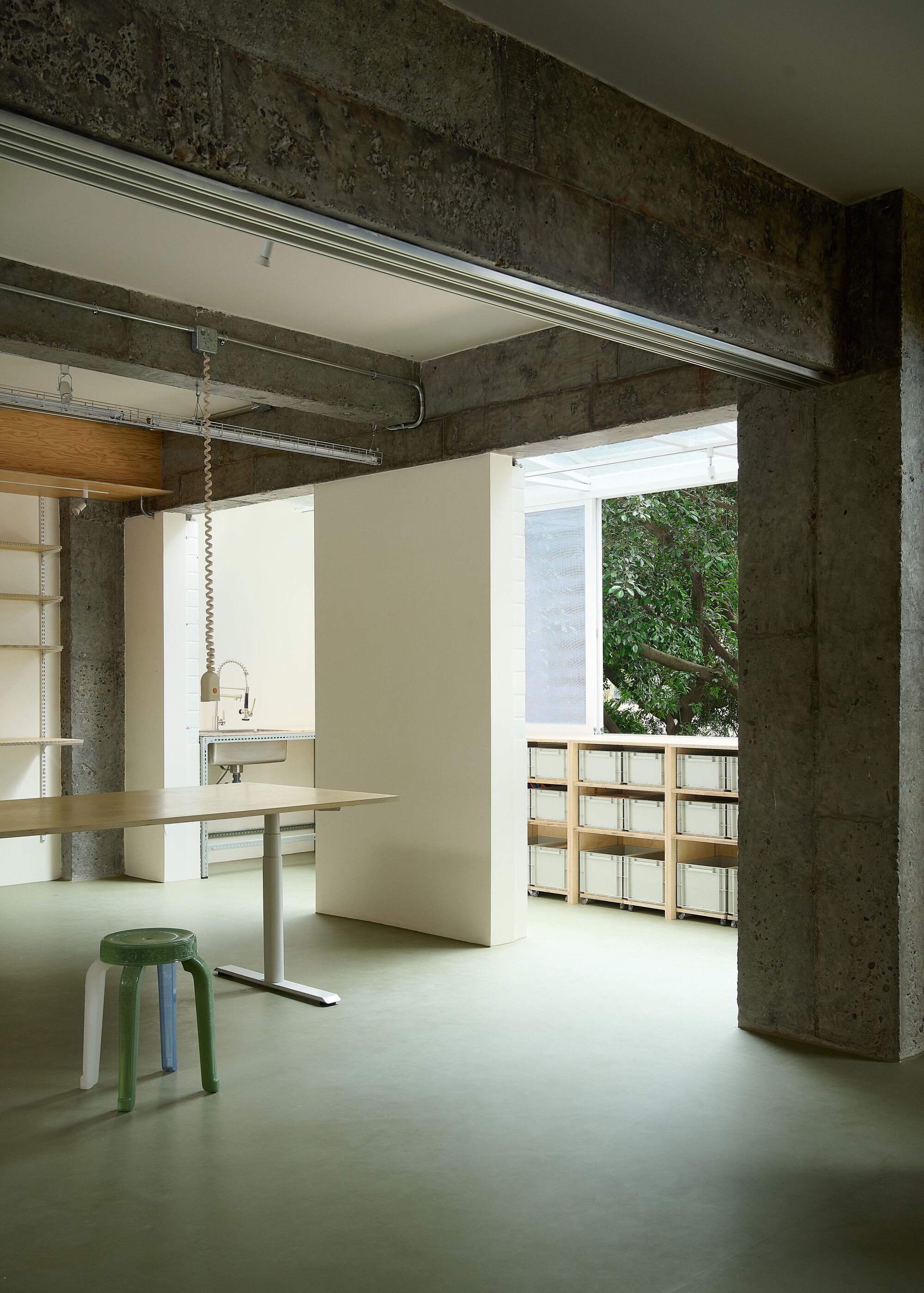 Open workspace with polished concrete floor and adjustable-height desk flanked by heavy concrete columns