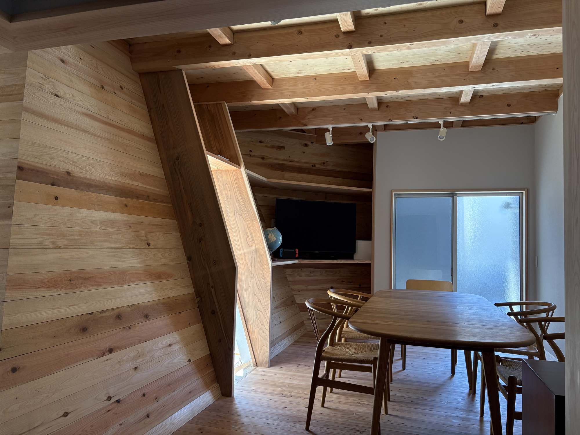 Dining area with exposed timber beams and built-in wood stair leading to upper loft space