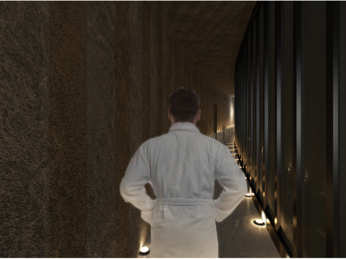 A dimly lit stone corridor uses texture and warm floor lighting to heighten the sensory transition into the thermal spaces