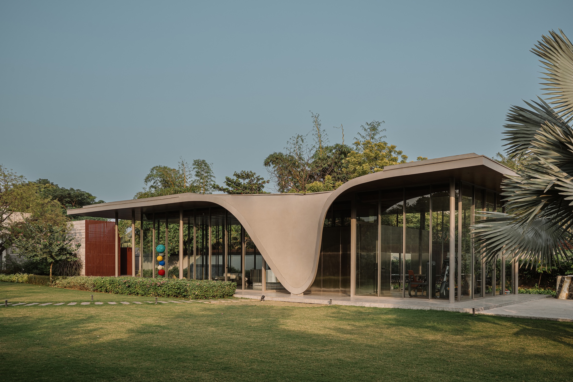 Garden elevation showing the double-curved roof connecting two glazed volumes across open lawn