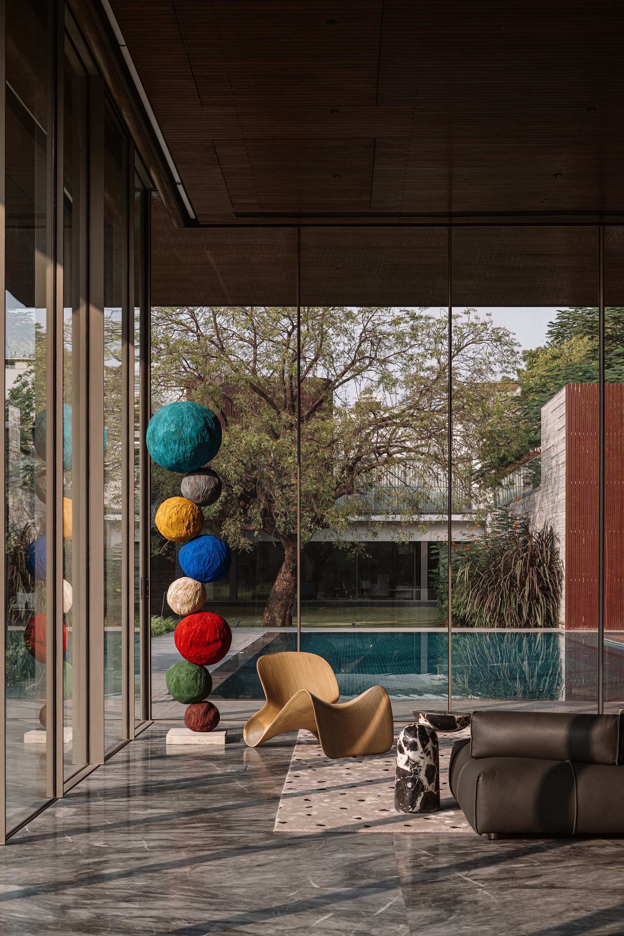 Interior corner with floor-to-ceiling glass looking out to the pool and a hanging sculpture of colored spheres
