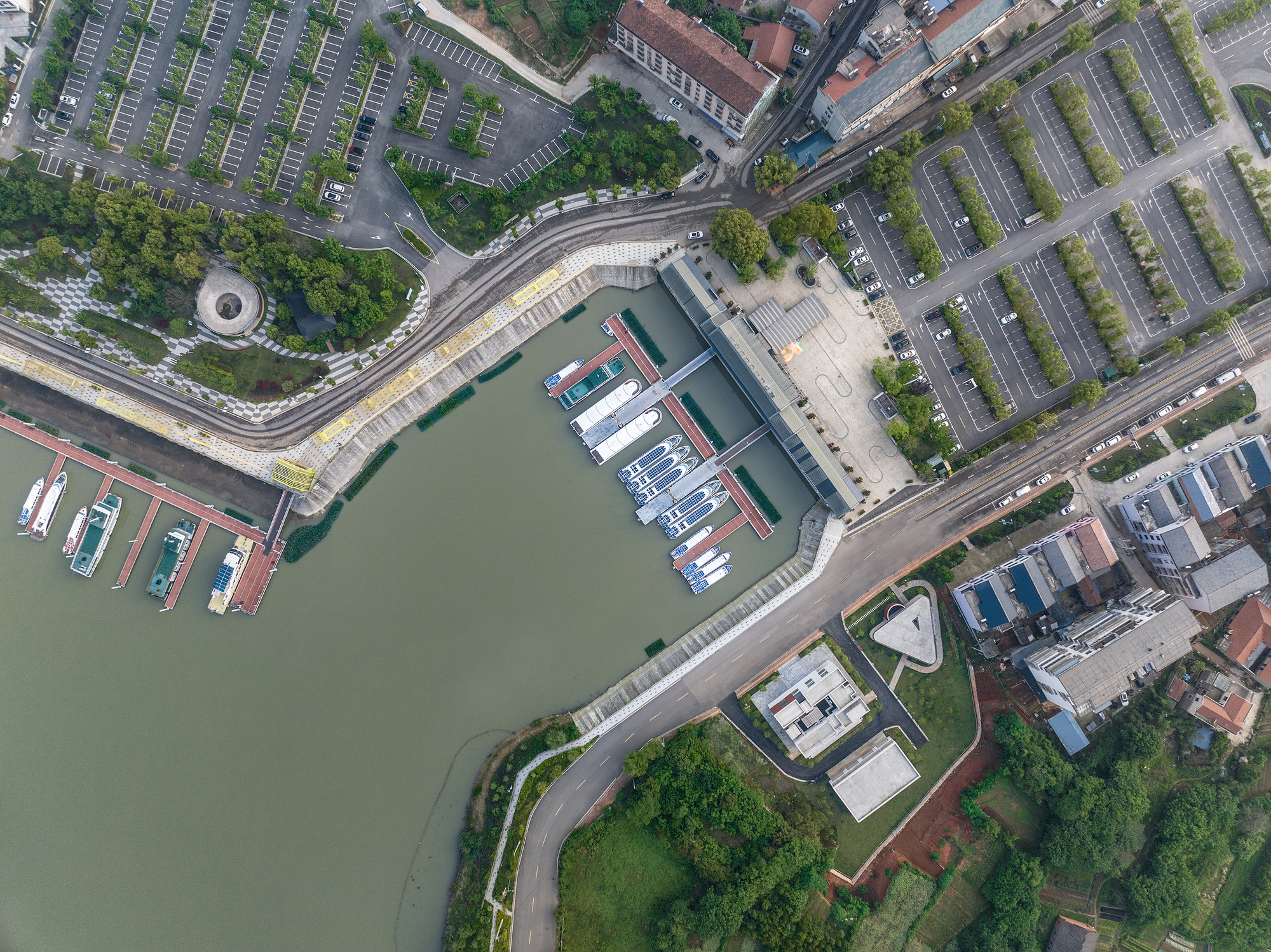Aerial view of the building positioned between a marina with boats and surrounding parking lots