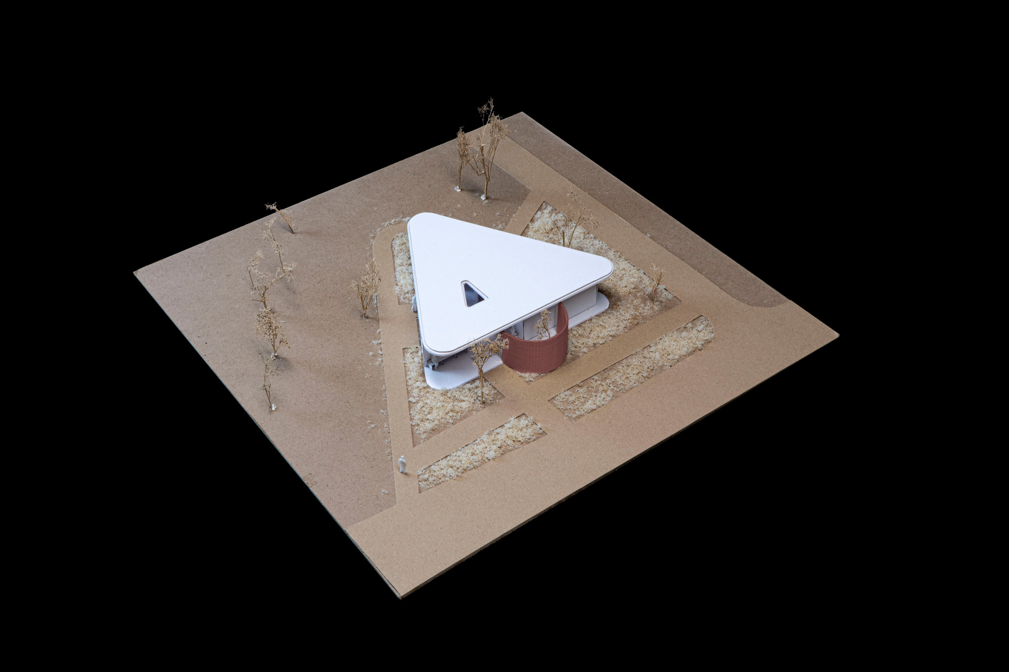 Physical model showing a triangular roof over a cylindrical volume set within terraced landscaping and planted beds