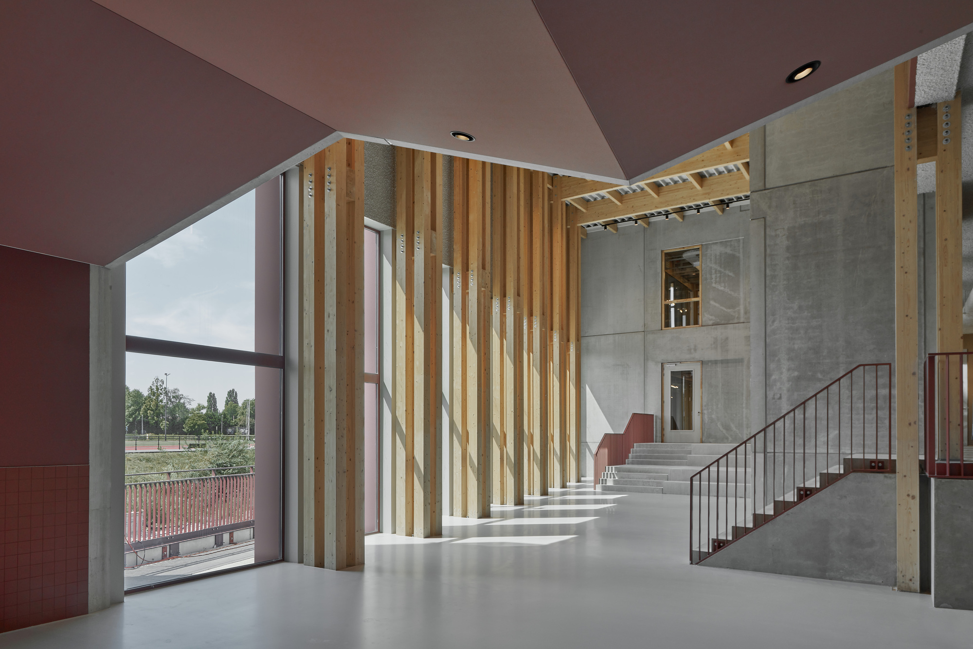 Double-height foyer with vertical timber slat screen and concrete stair under angular ceiling planes