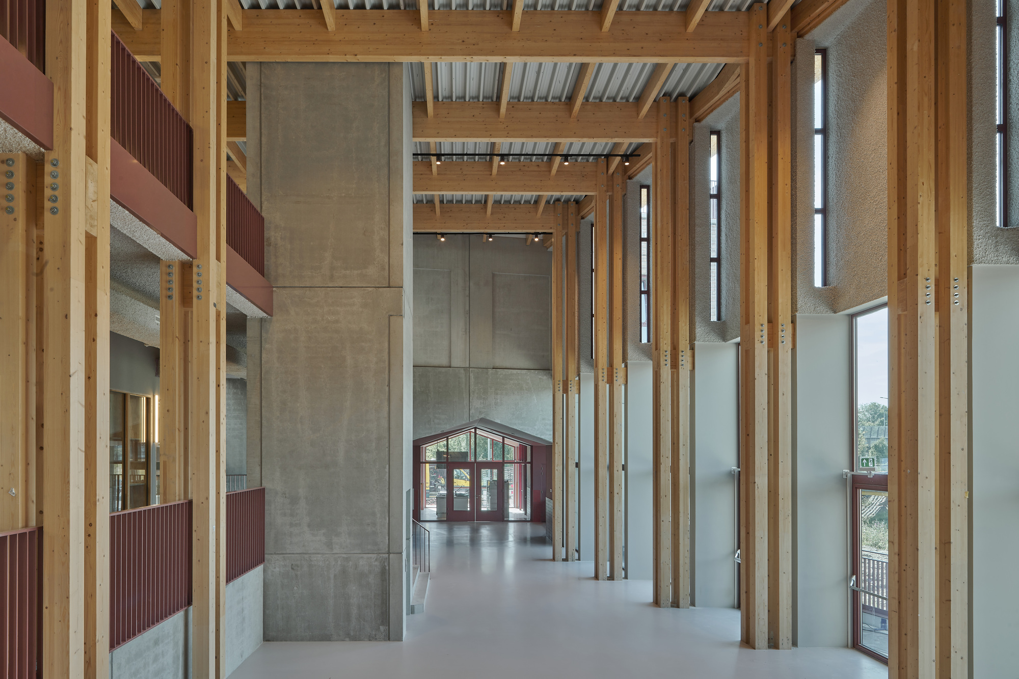 Interior hall with exposed timber beams and vertical wood columns framing views to exterior doorway