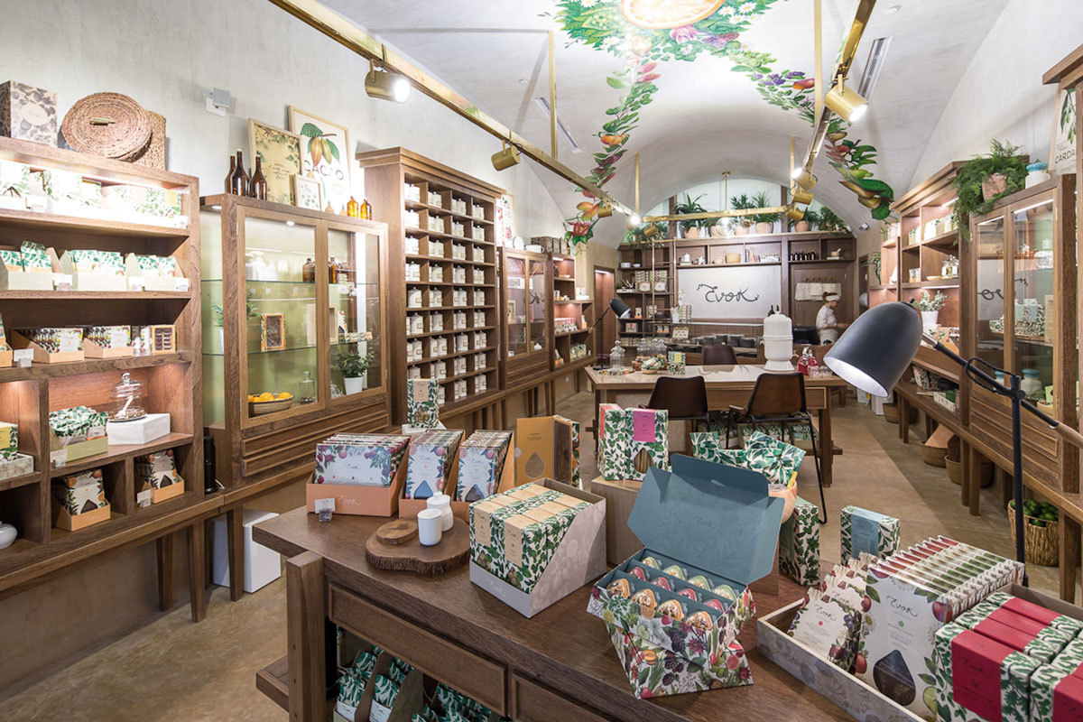 Packaged goods on a wooden table in the foreground, with a vaulted painted ceiling and shelving receding toward the back wall