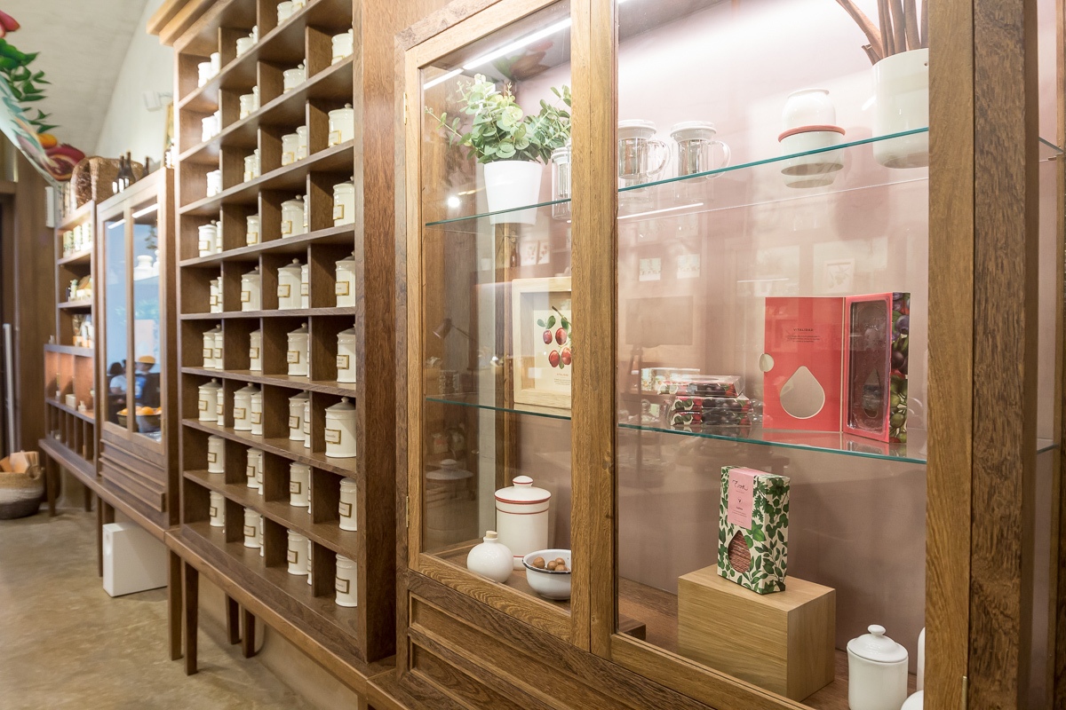 Oak display cabinets with glass doors and shelves of white lidded tins, ceramics and boxed products along the wall