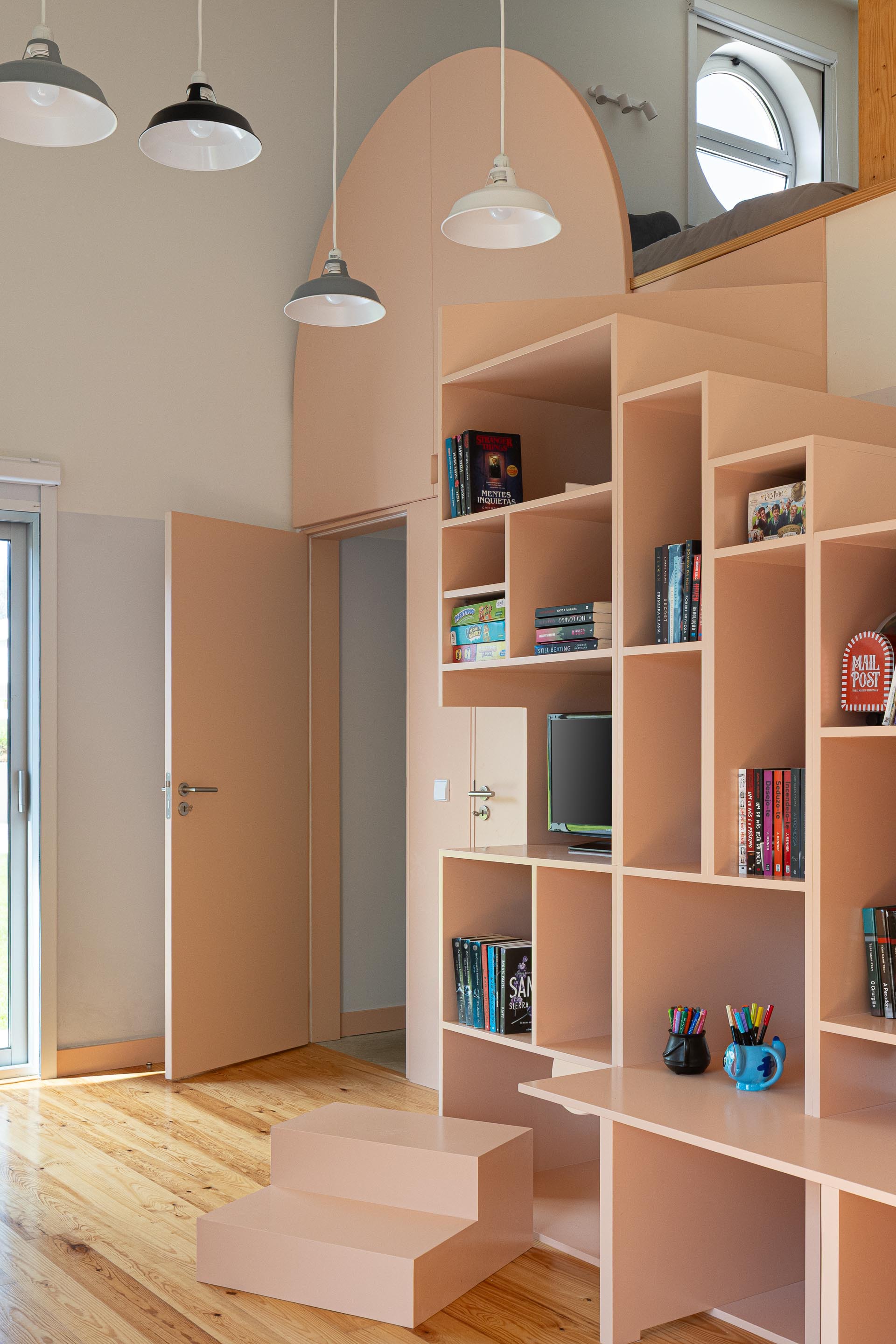 Pink plywood shelving unit with arched opening and stepped base under pendant lamps