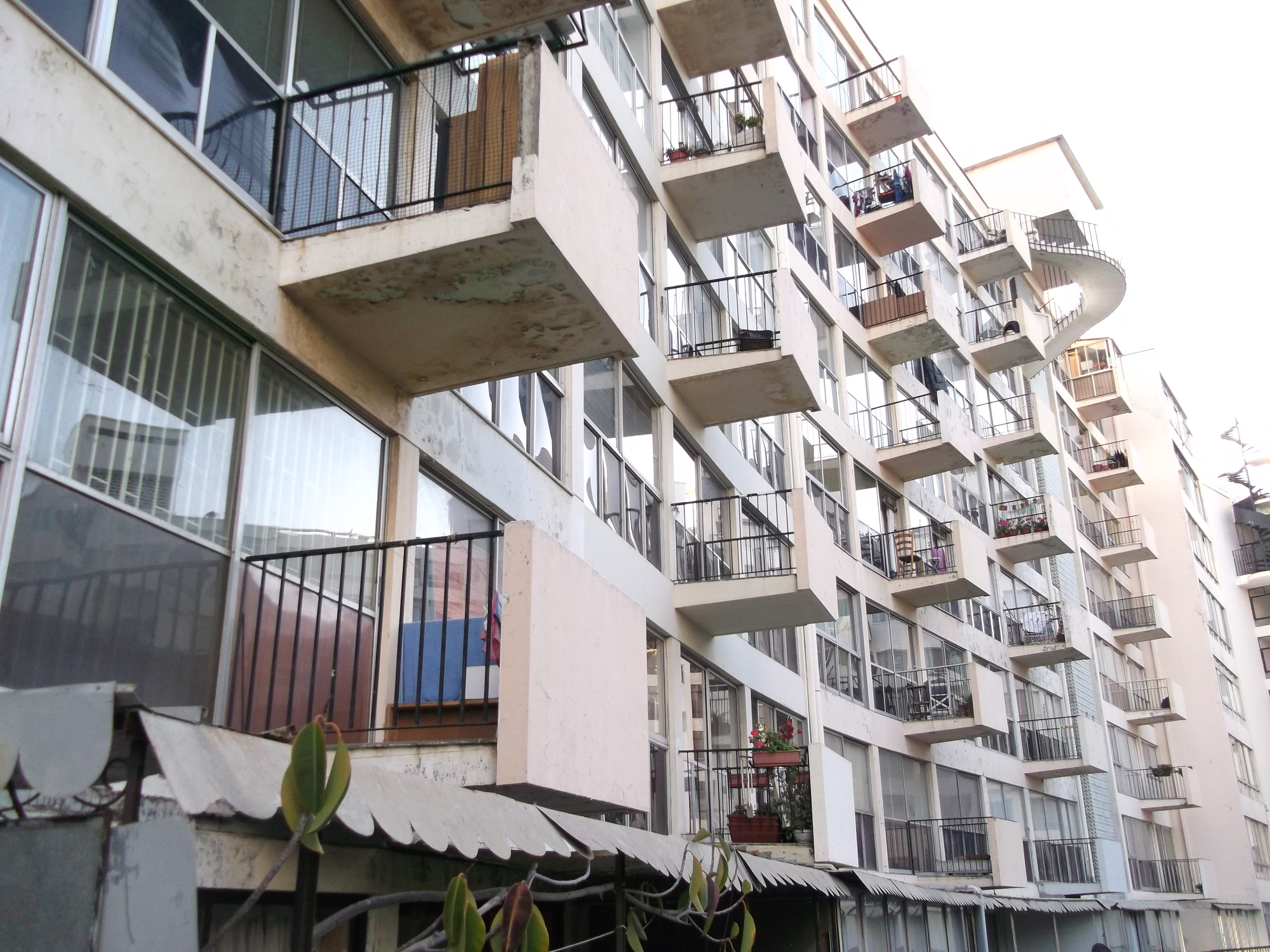 Junction between the cantilevered concrete balconies and the white facade of the adjacent tower block