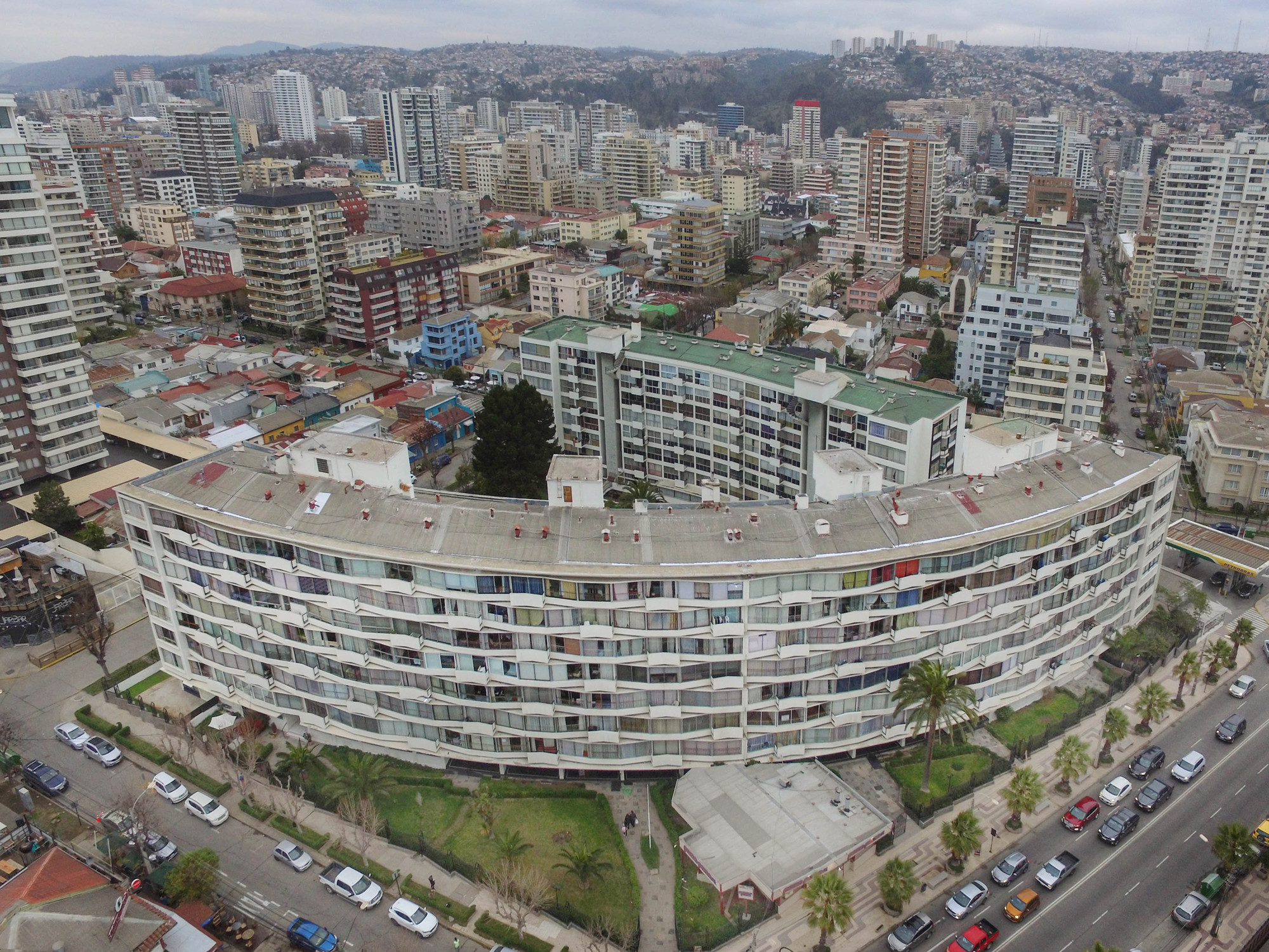 Aerial view of the curved residential block with continuous balcony ribbons set within the surrounding urban fabric