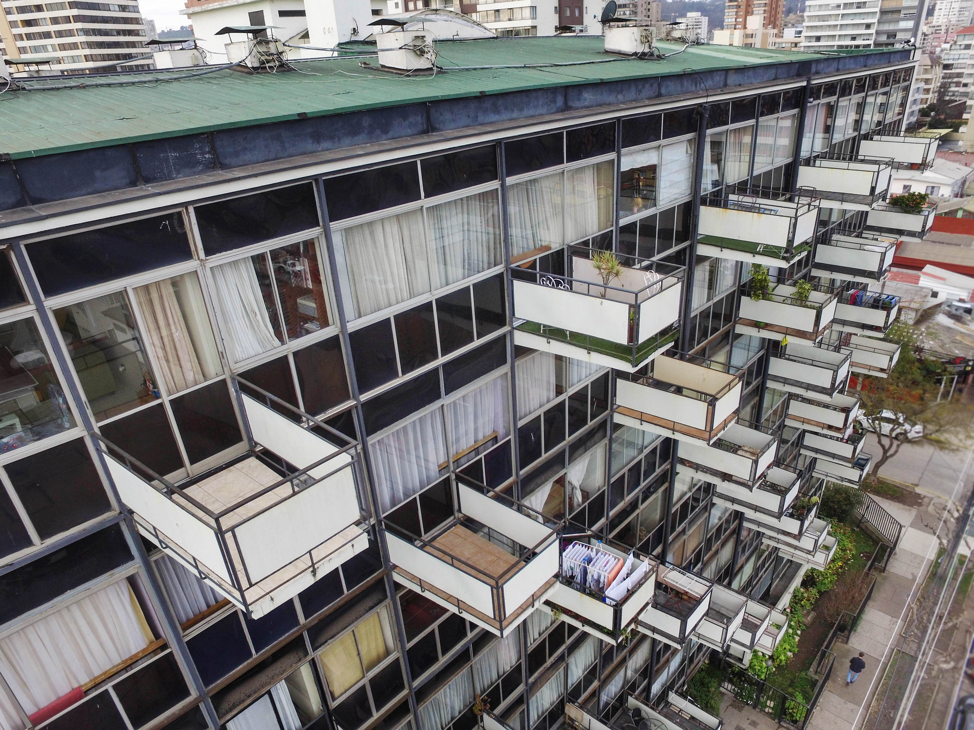 Angled view of the residential block showing staggered balconies and green rooftop at dusk