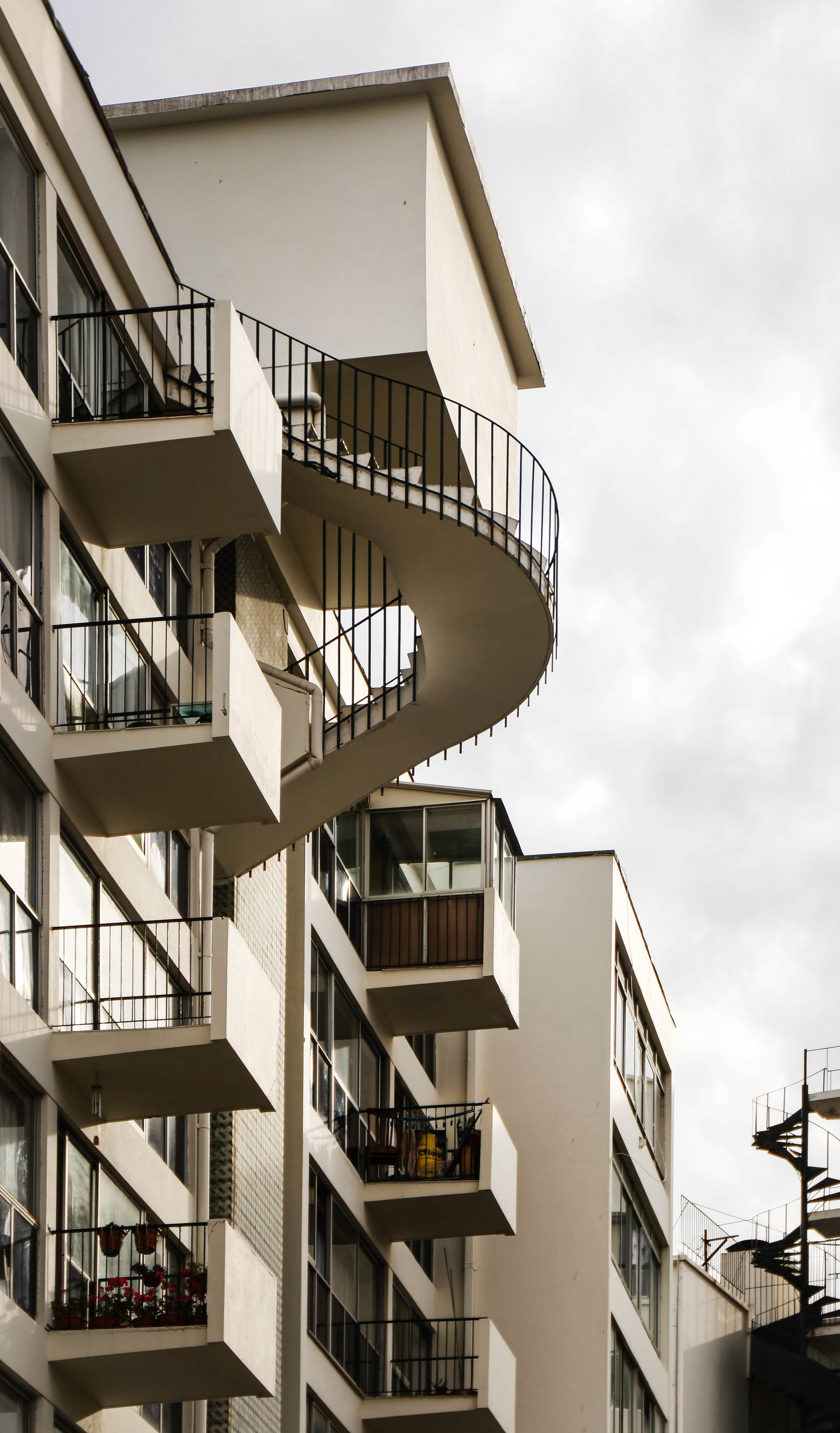 Projecting circular stair tower with metal railings against an overcast sky