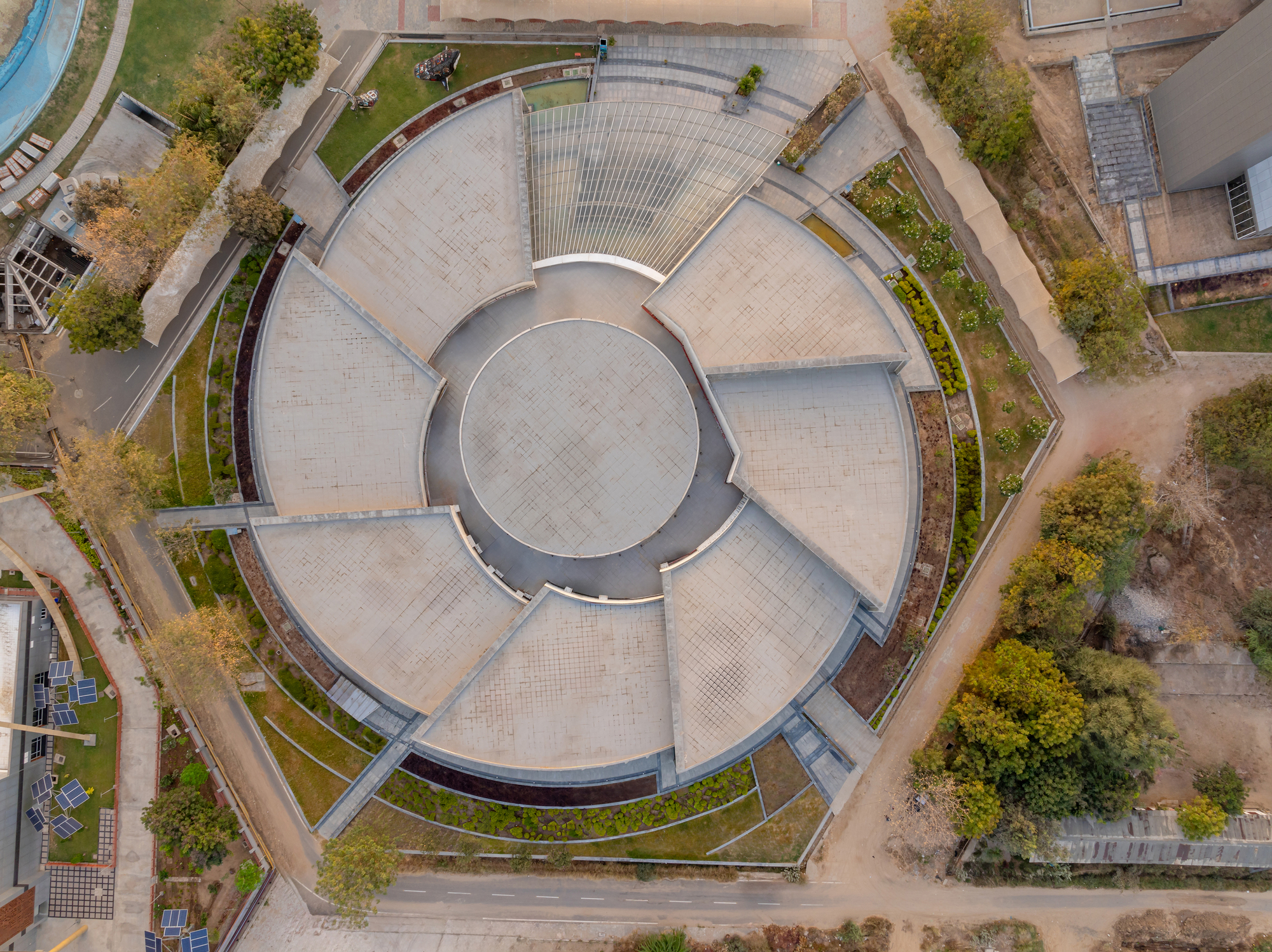Top-down view of the circular paved plaza with radial symmetry and planted borders between roof sections