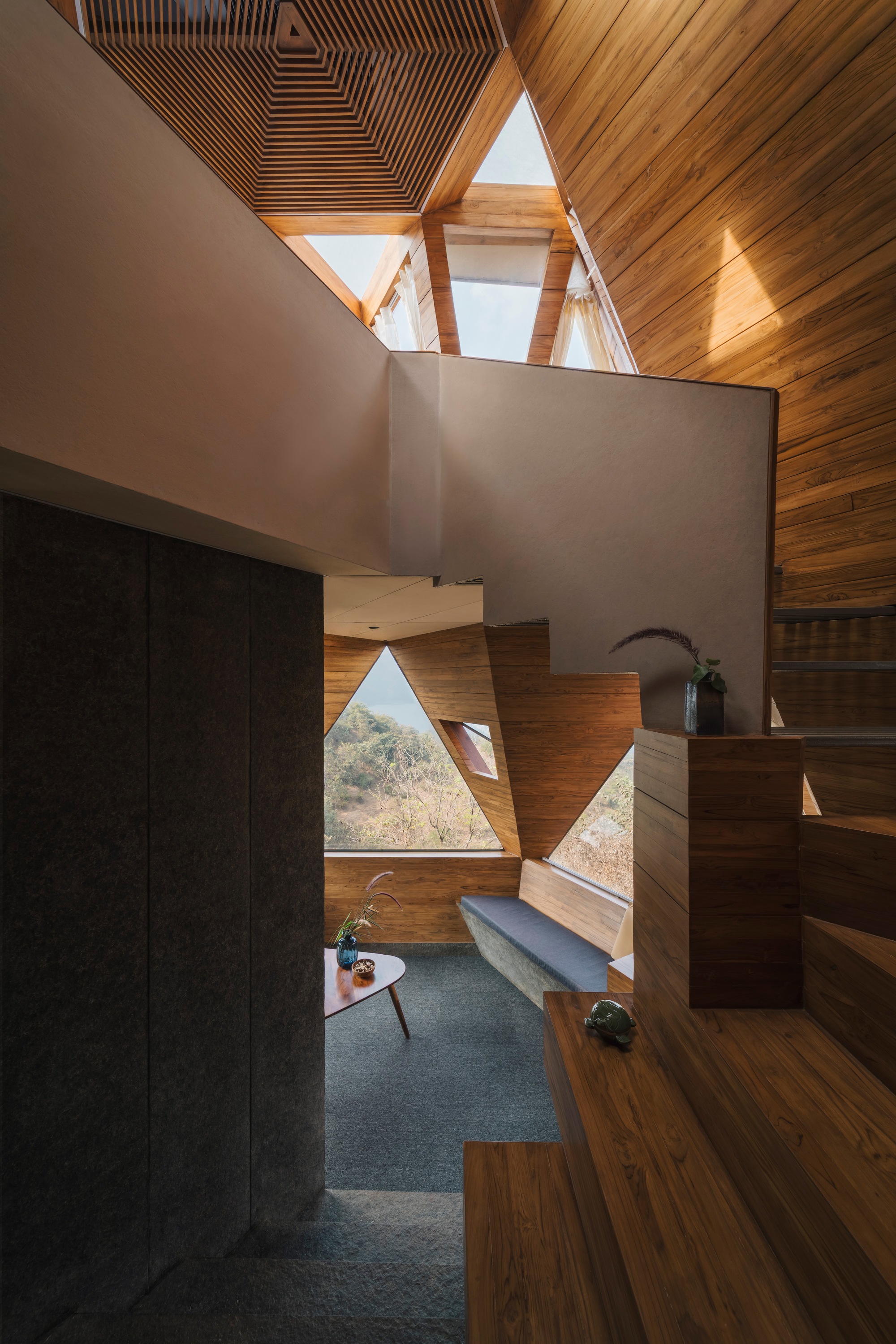 Interior view of timber-lined volume with triangular windows and floating planes under ribbed ceiling