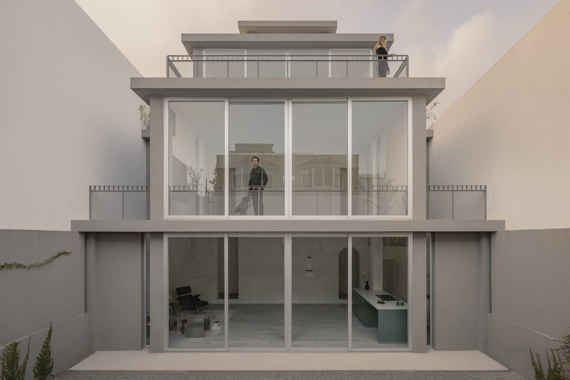 Rear facade with stacked glazed volumes and recessed balconies under overcast sky