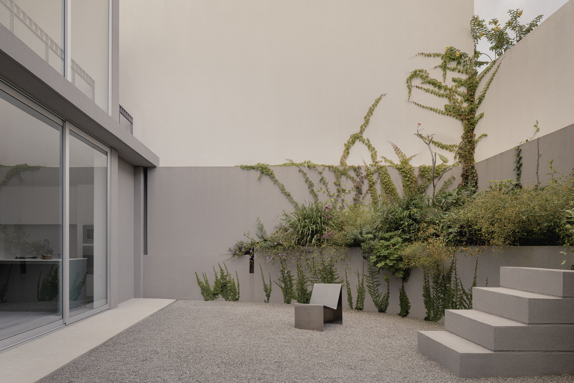 Courtyard with raised planter beds and climbing vines against rendered walls