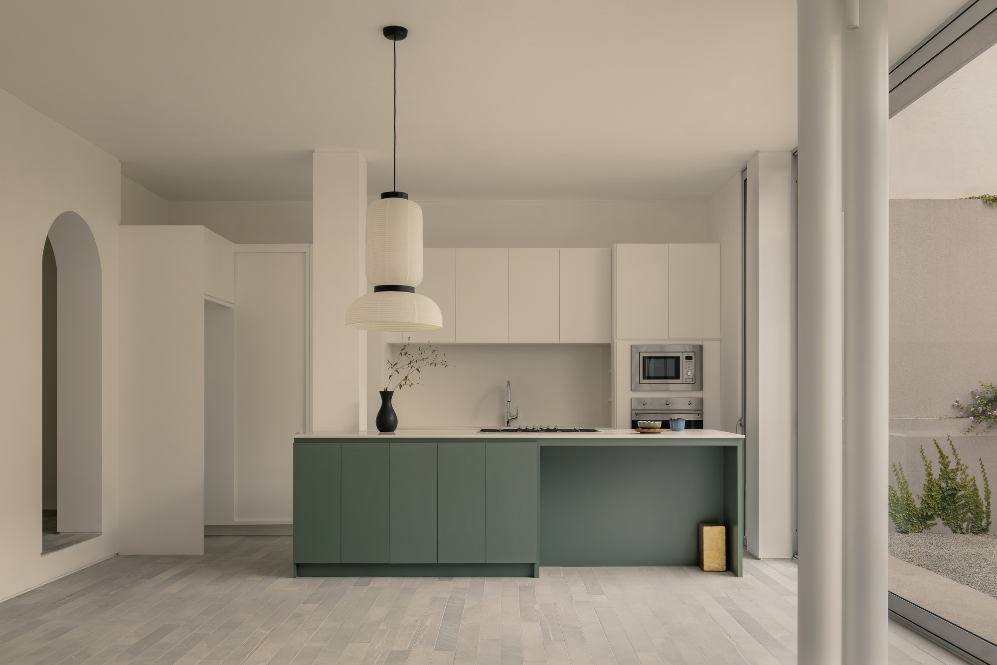 Kitchen with green island cabinetry and white upper cabinets beneath pendant light
