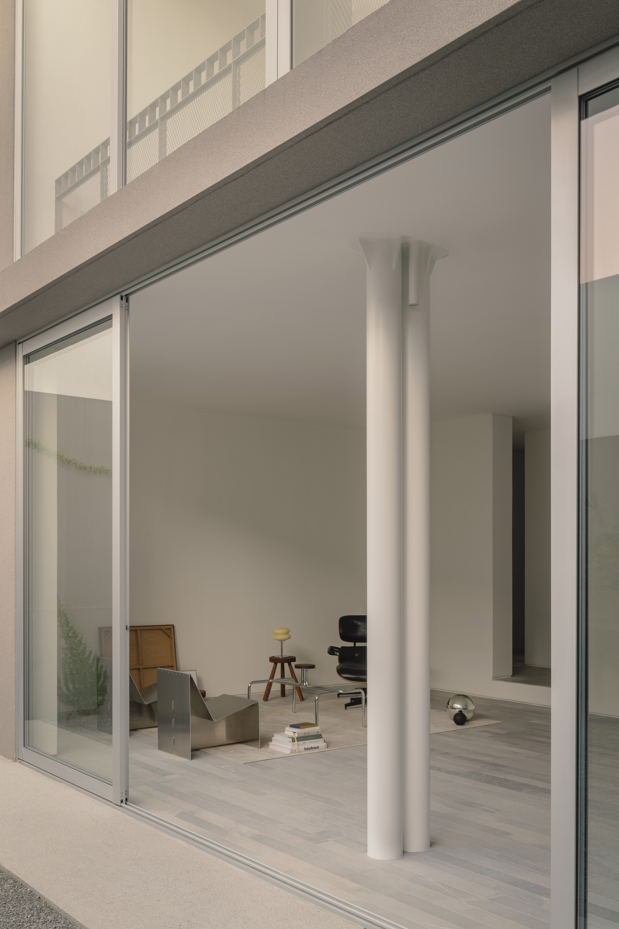 Interior view through open sliding doors showing white column and furniture in soft afternoon light