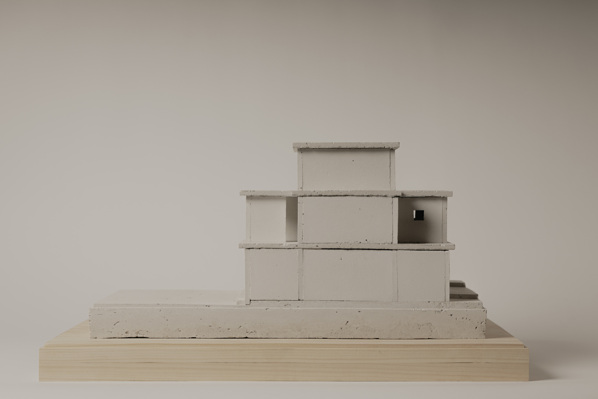 Concrete model showing a stepped volumetric composition on a wooden base