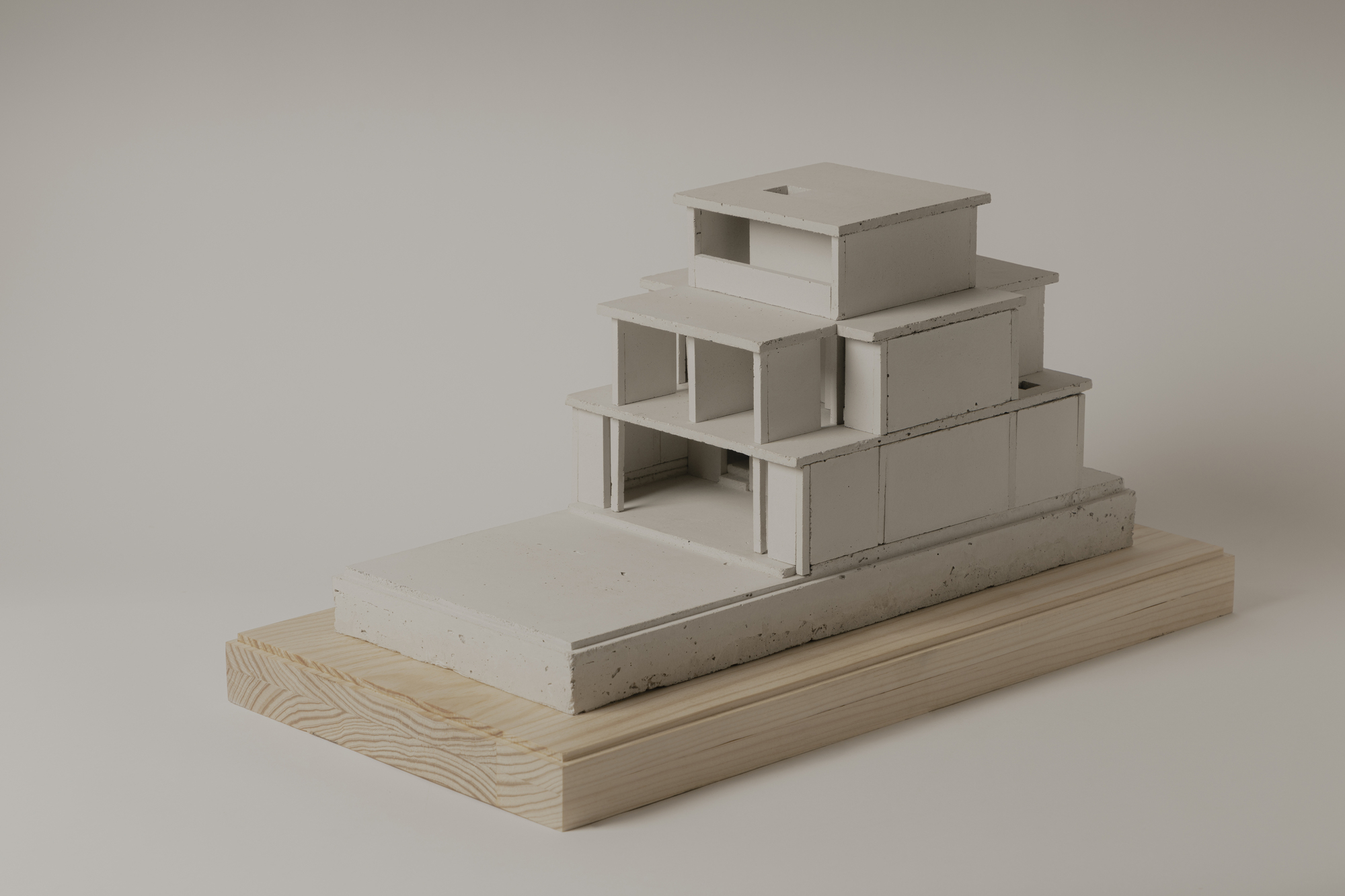 Side view of the stepped massing model with exposed interior spaces and concrete plinth