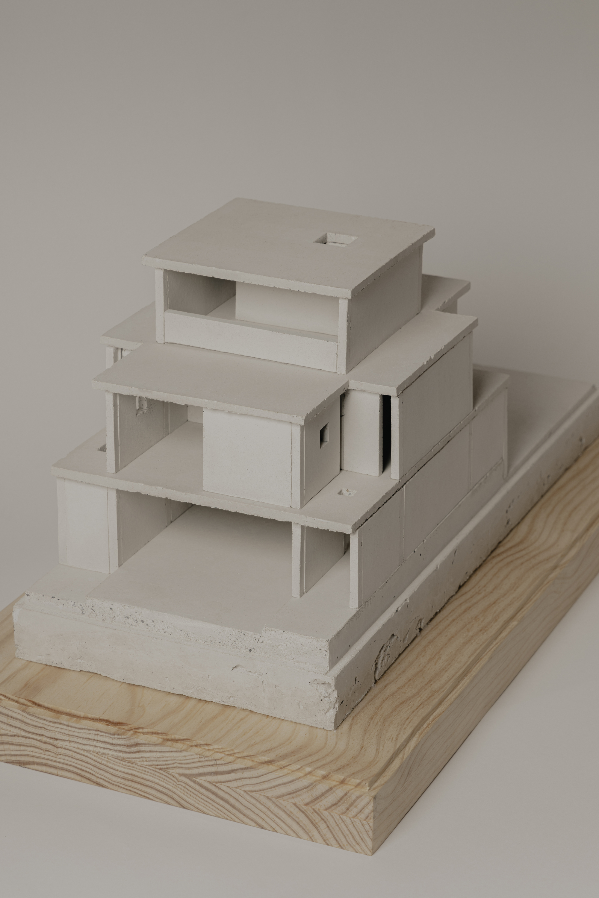 Corner view of the terraced model with layered horizontal planes on wood and concrete plinths