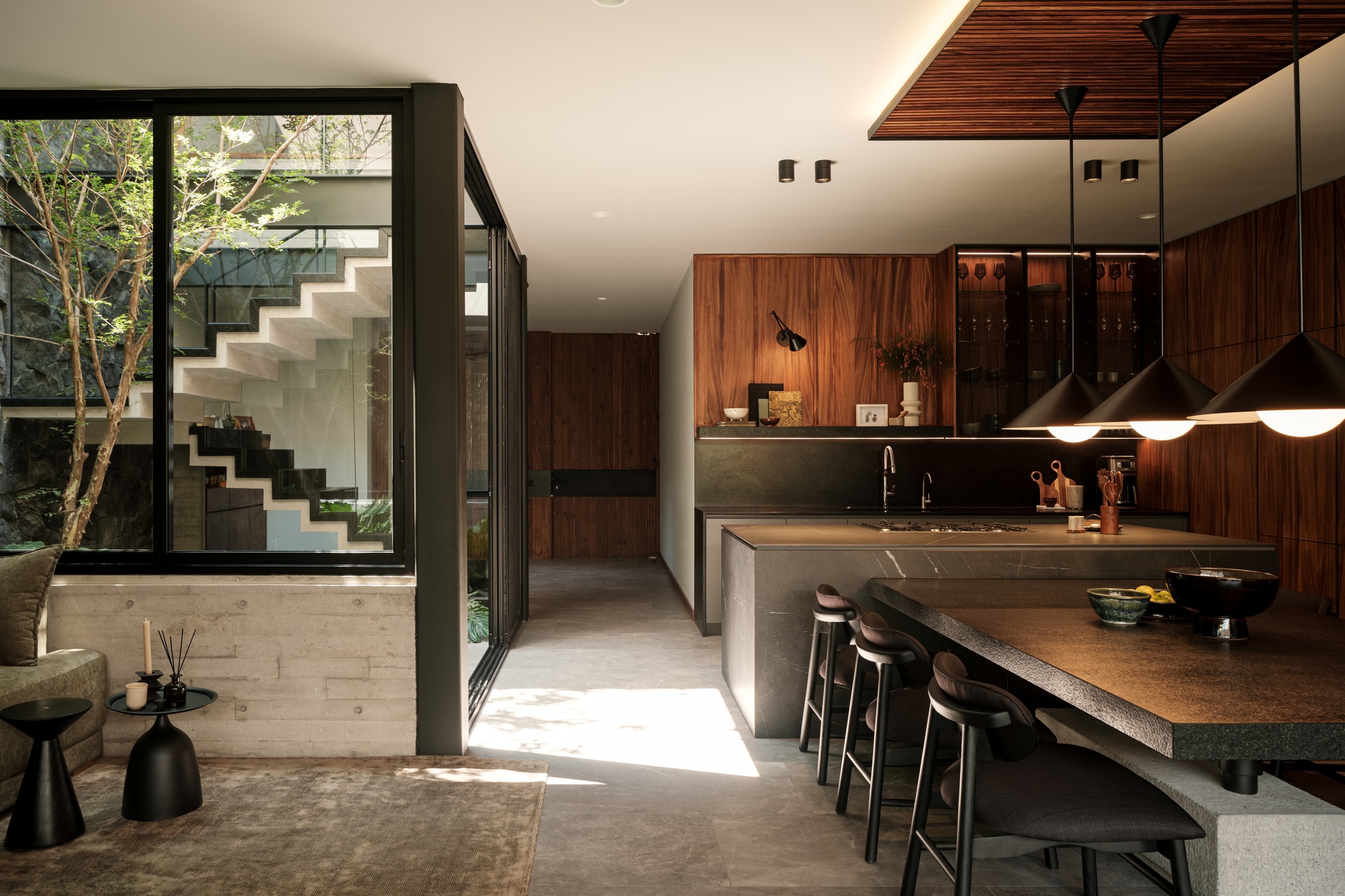 Kitchen island with dark stone countertop overlooking an interior courtyard through floor-to-ceiling glazing