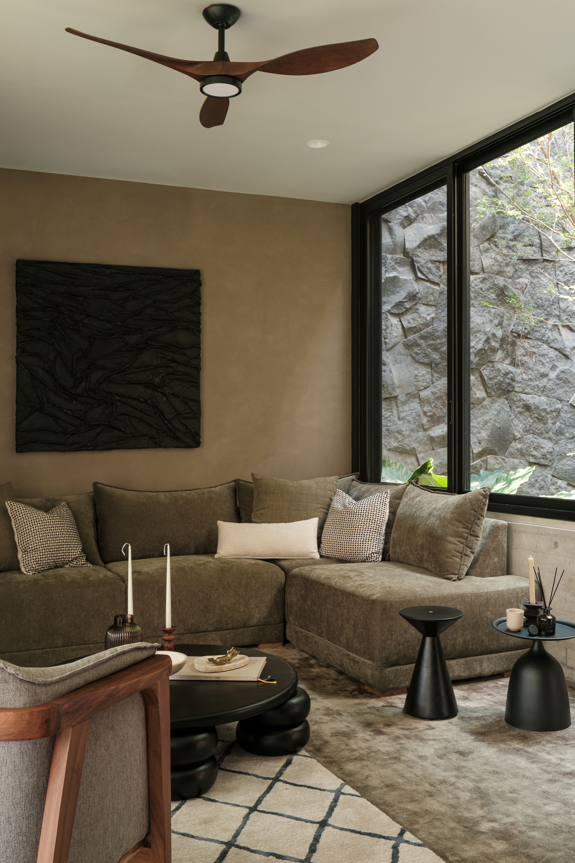 Seating area with corner glazing framing a view of rough-hewn stone courtyard wall and planting