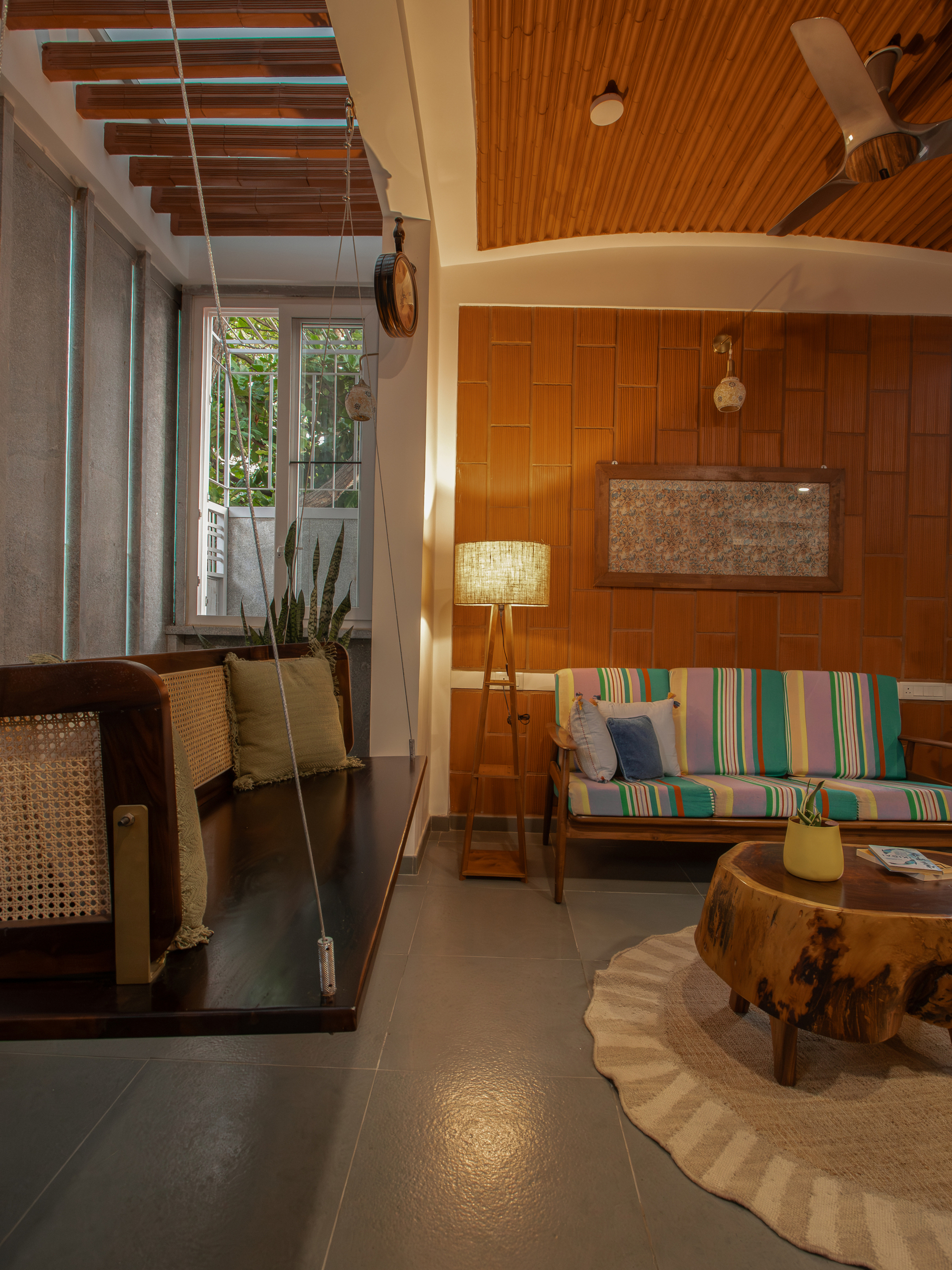 Living area with curved timber ceiling vault and suspended swing near the window at dusk