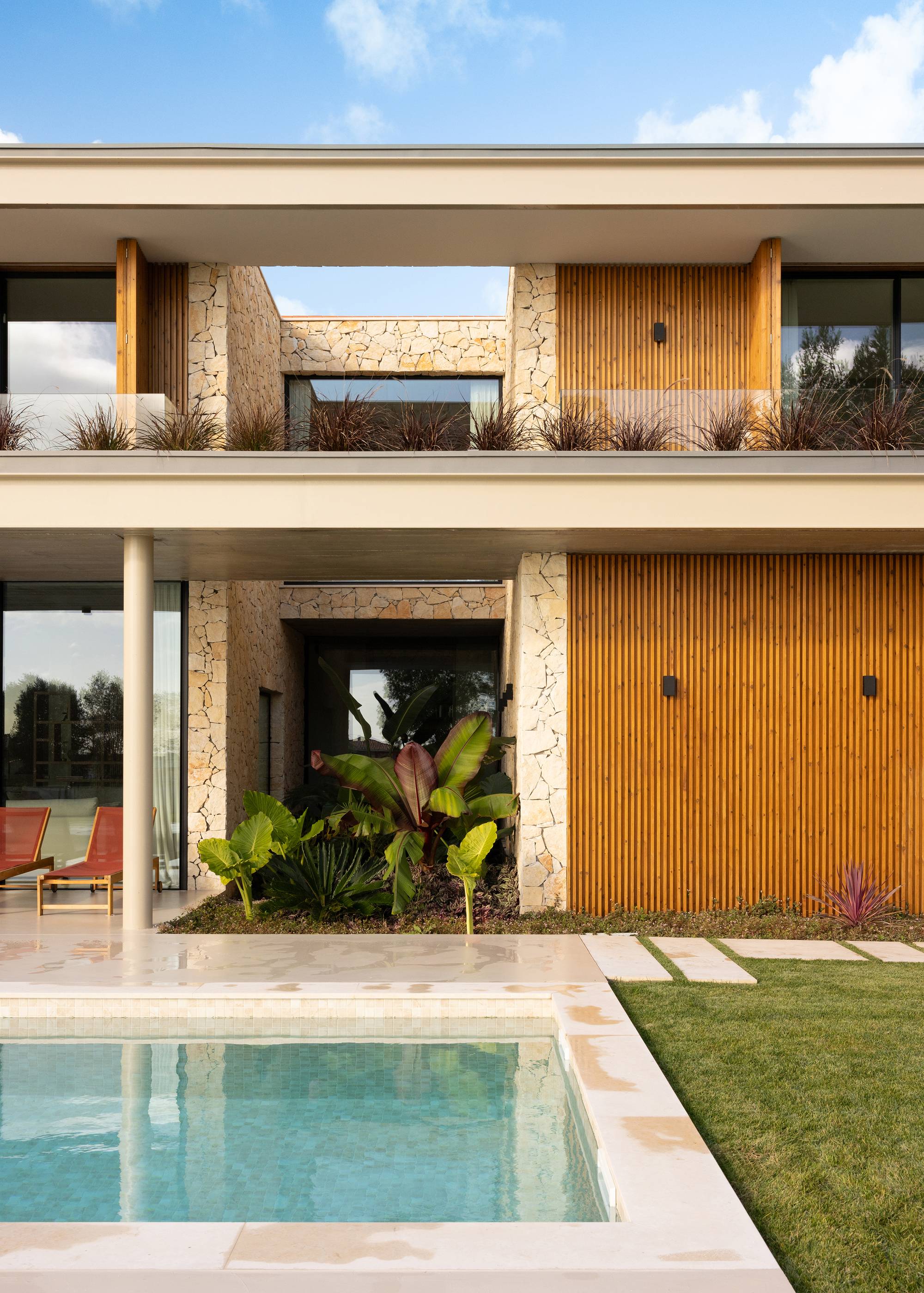 Poolside elevation showing stone piers, timber slat panels and planted terrace beds with tropical foliage