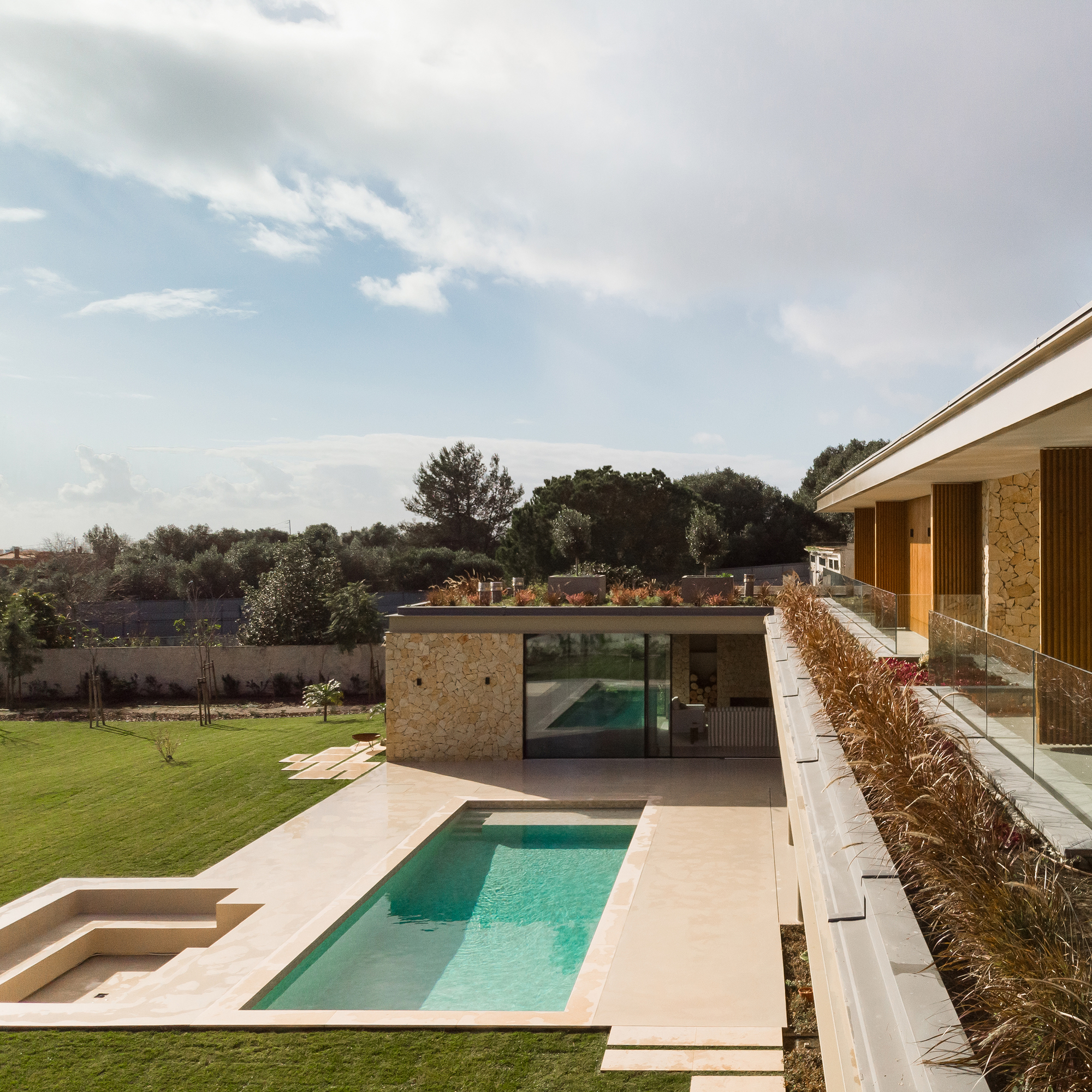 Garden courtyard with pool terrace, stone pavilion, and planted beds along the lawn