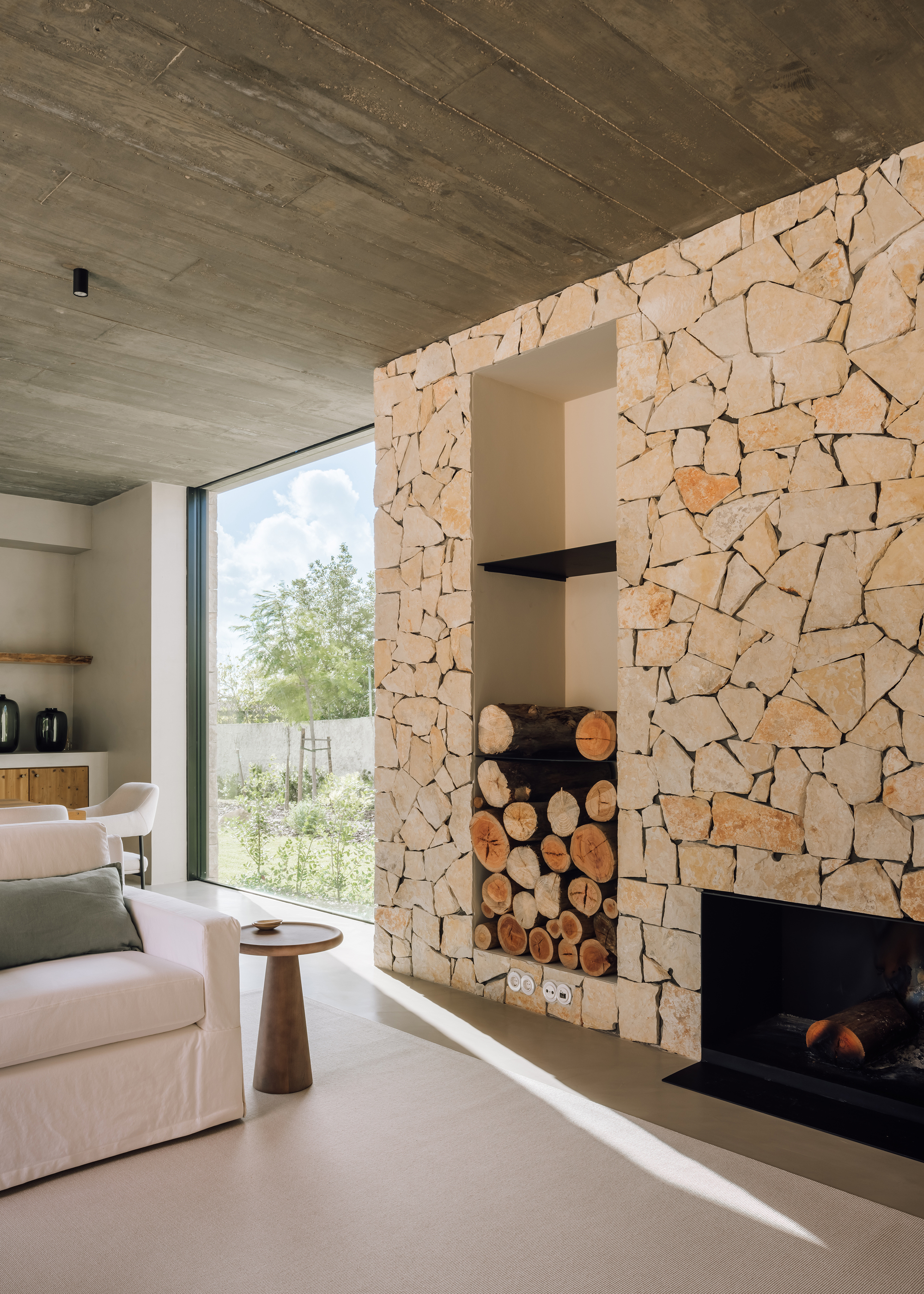 Living area with irregular stone fireplace wall and clerestory opening framing green courtyard beyond