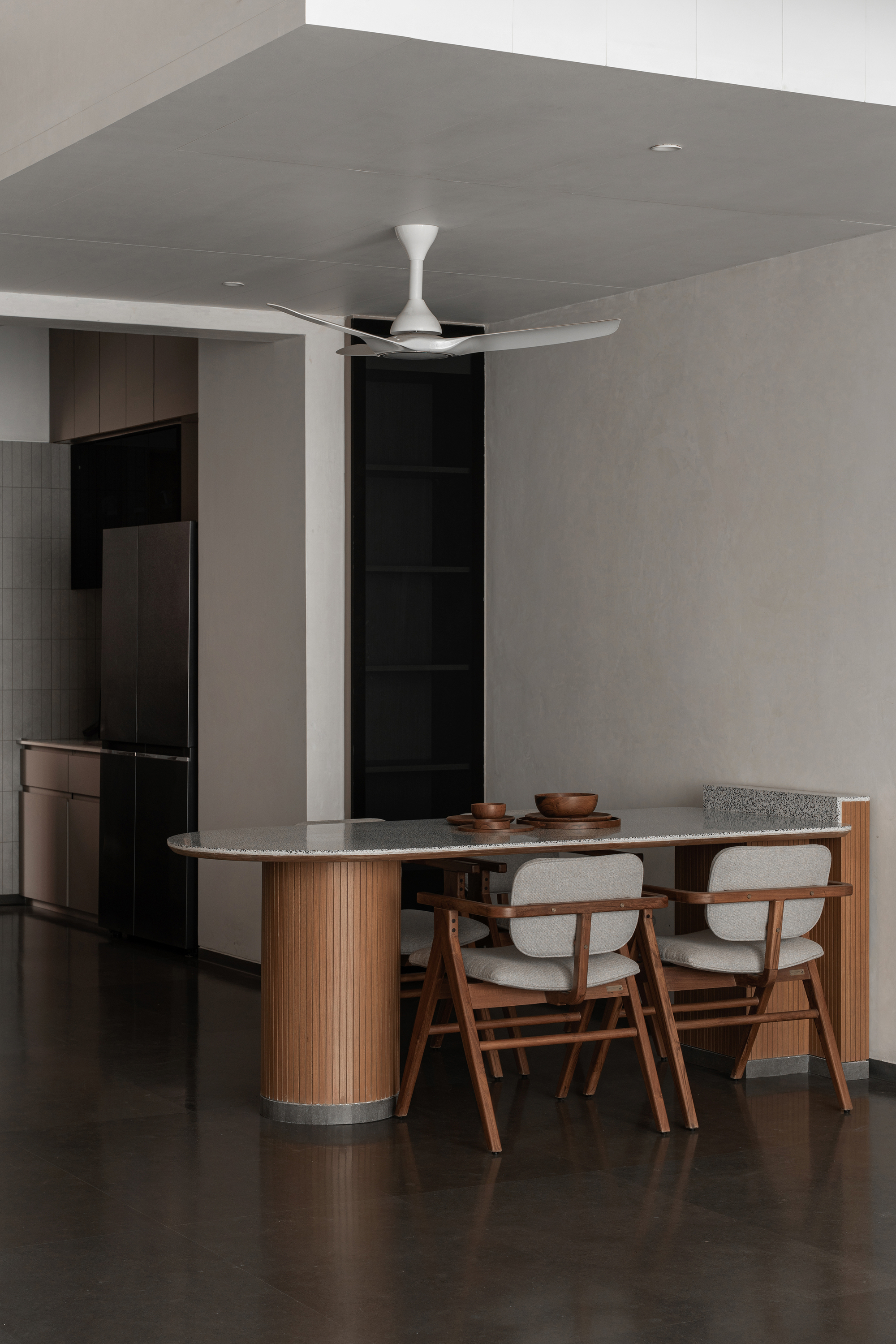 Dining table with fluted timber base and upholstered chairs beneath a ceiling fan