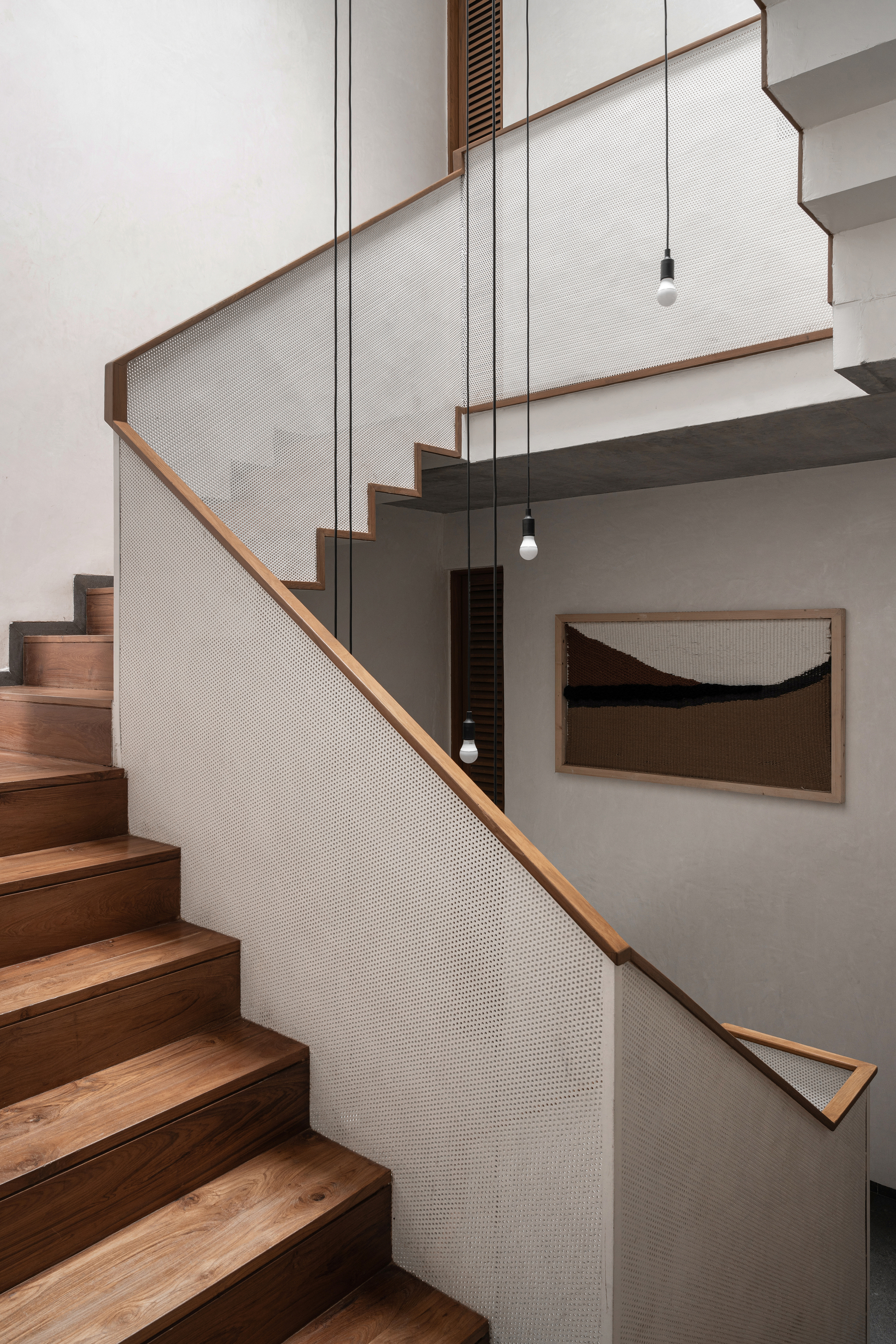 Timber staircase with mesh-paneled balustrade and pendant lights descending through the stairwell