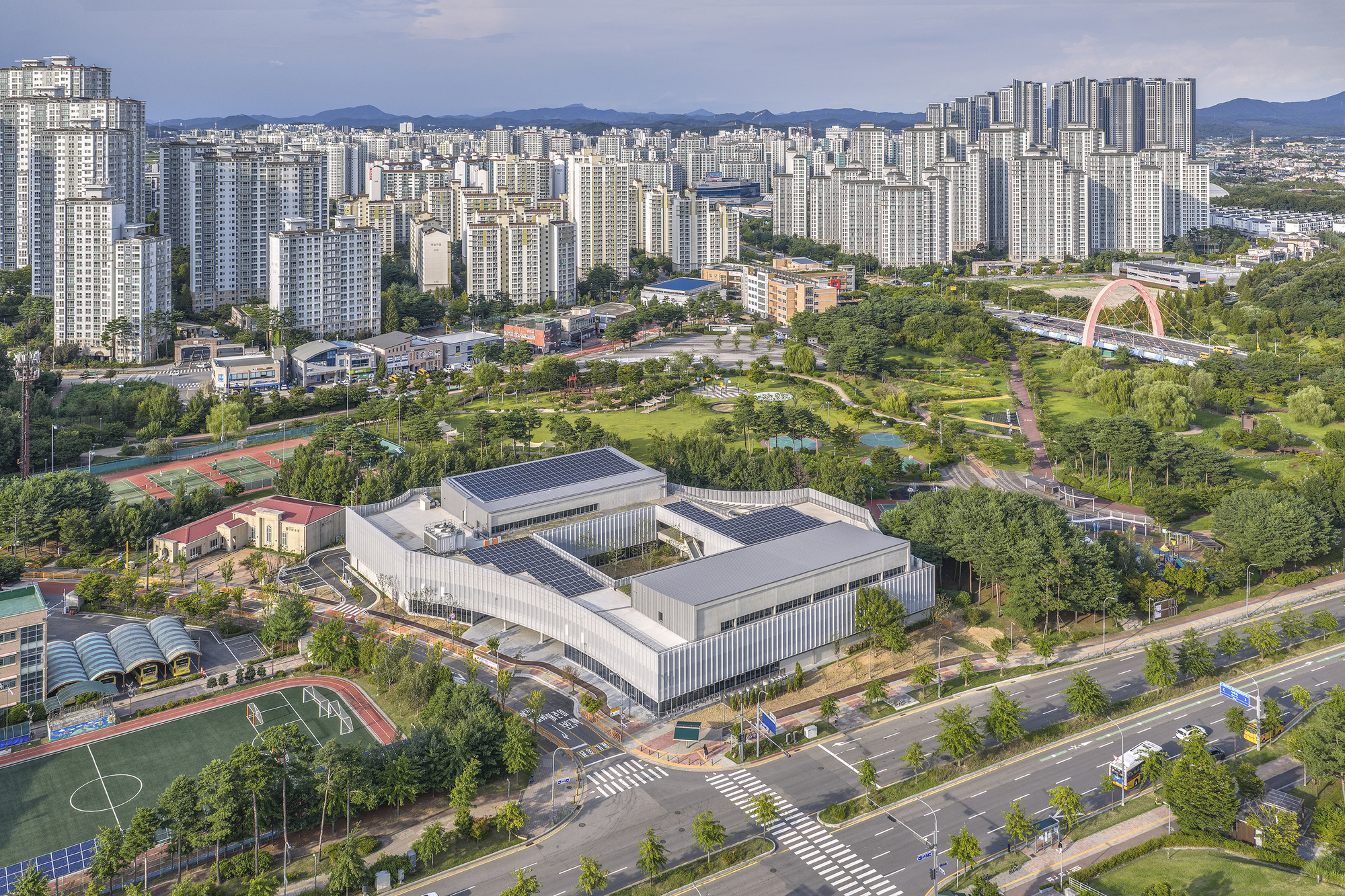 Aerial view of the interlocking white volumes surrounded by parkland and high-rise residential development