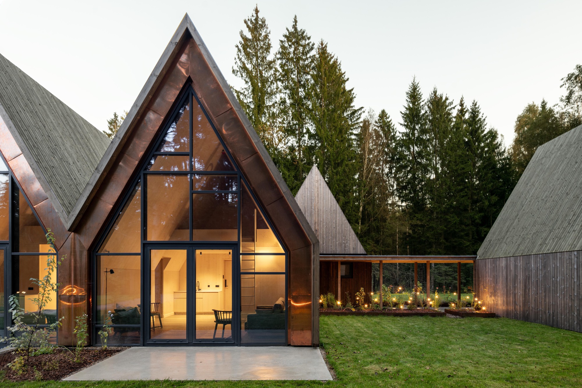 Illuminated gable pavilion with full-height glass facade at dusk