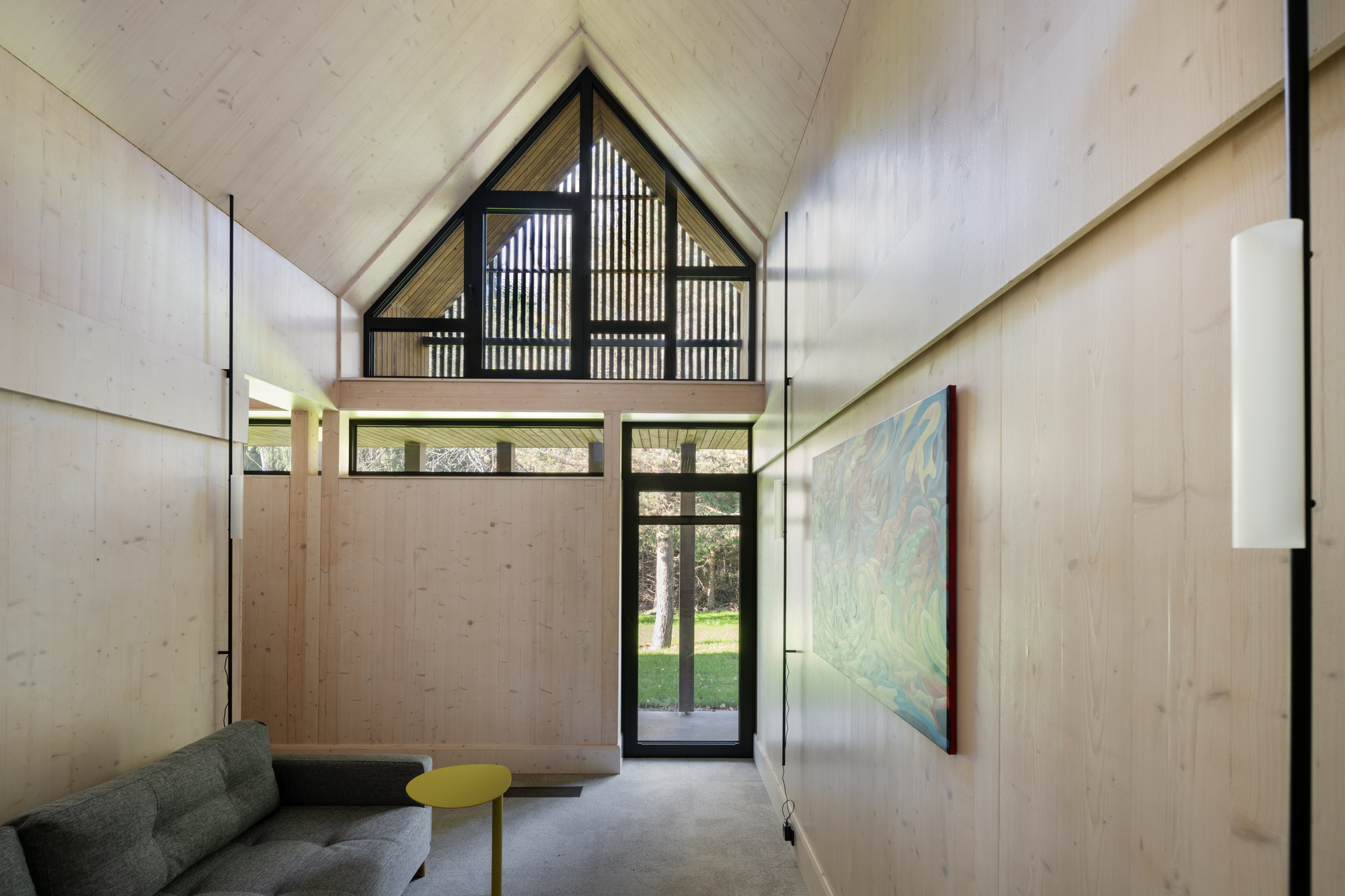 Double-height entry hall with plywood walls, vertical organ pipes, and a gabled clerestory window