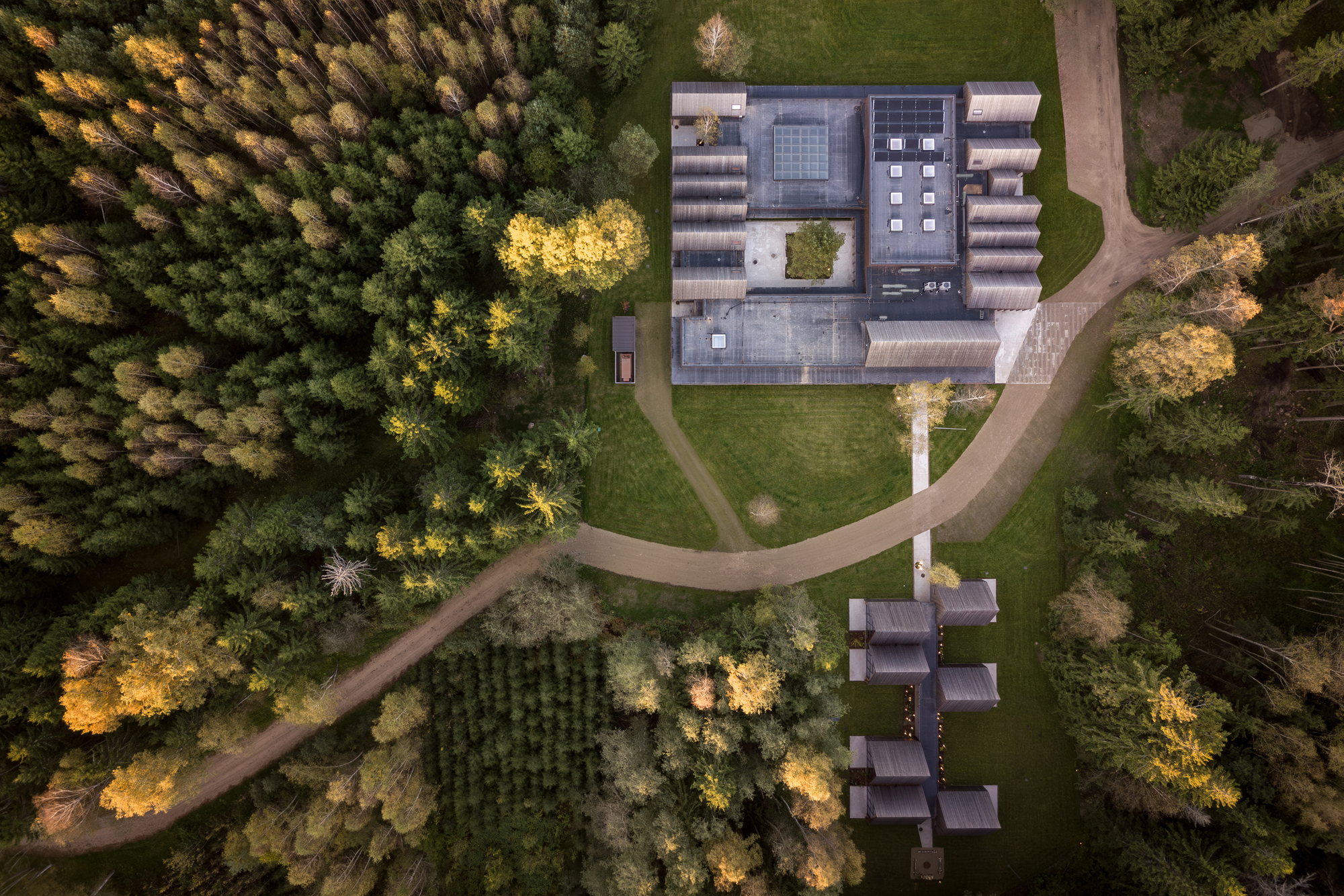 Aerial view showing the H-shaped plan with central courtyard surrounded by autumn forest