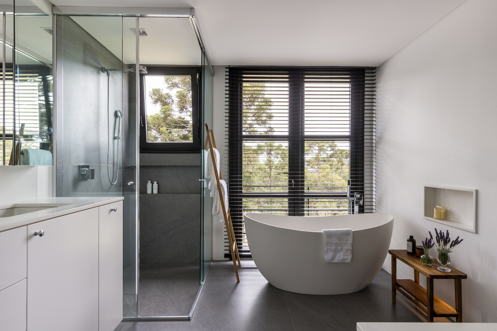 Bathroom with freestanding tub, glass-enclosed shower and horizontal timber blinds framing the window