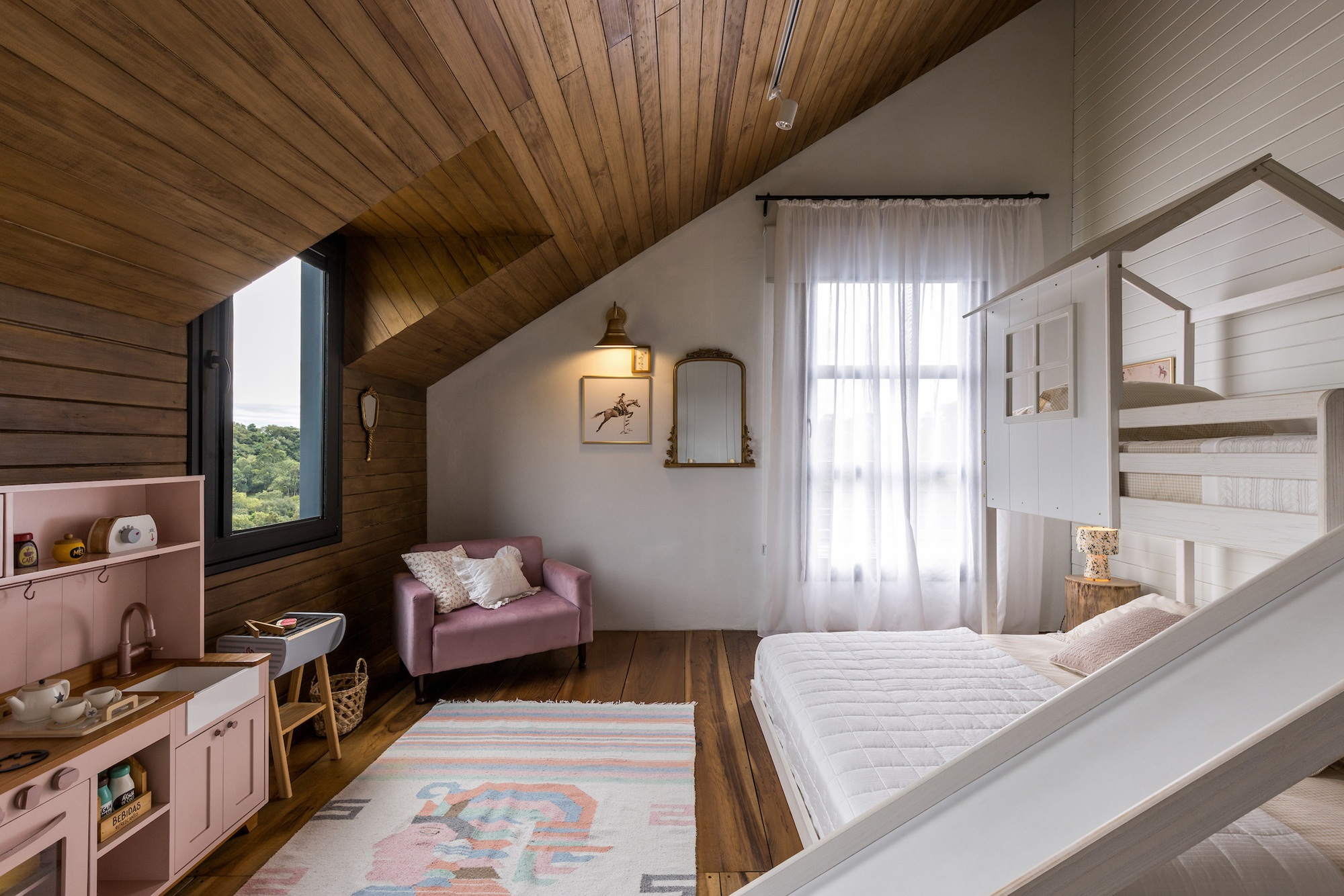 Bedroom with vaulted timber ceiling, pink kitchenette and white bunk bed structure in daylight