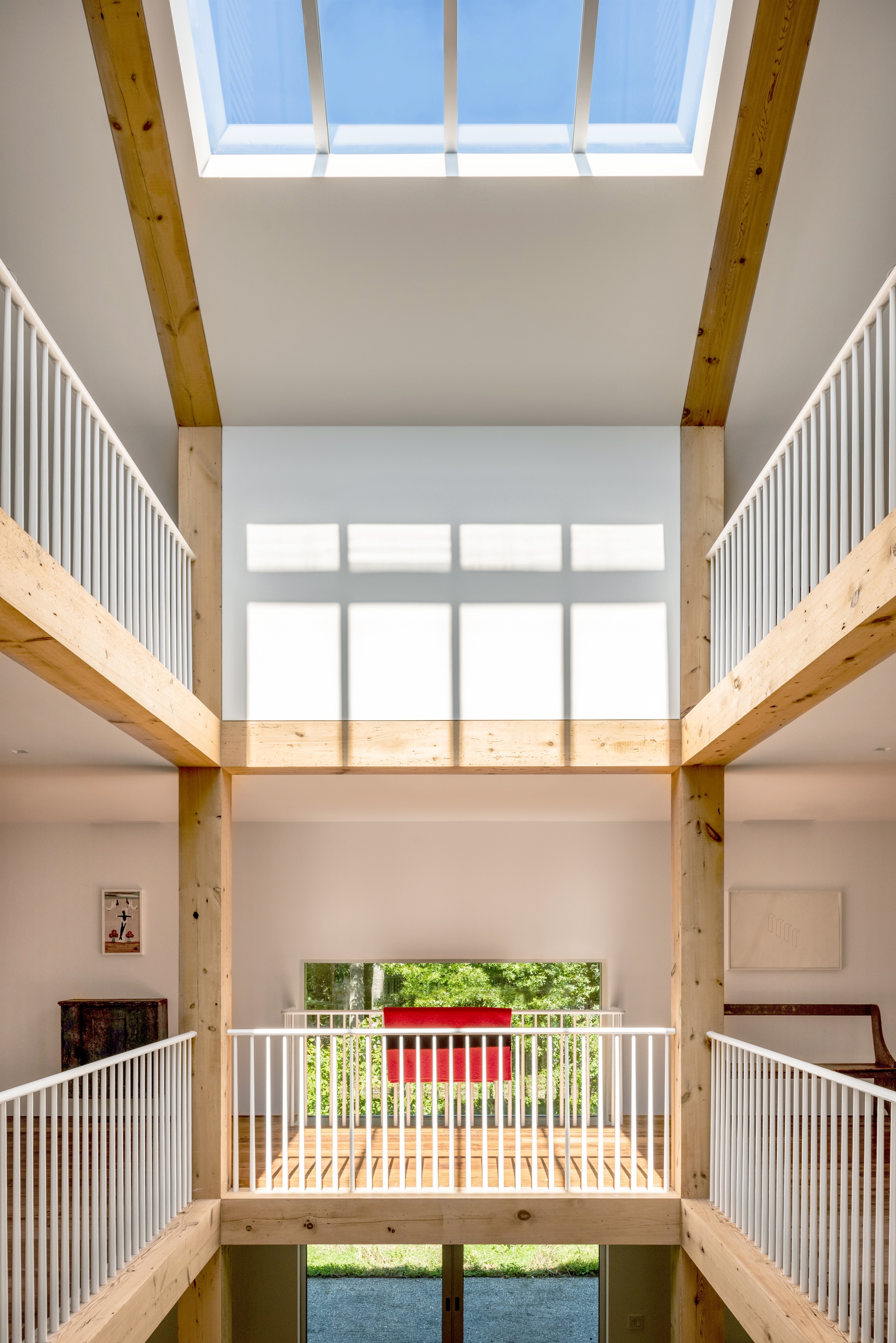 Central atrium with layered timber balconies and rectangular skylight framing the ceiling