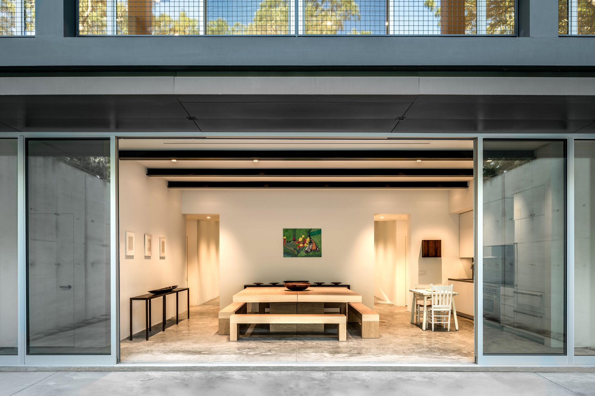 Open garage door revealing the interior workspace with timber benches and exposed beam ceiling at dusk