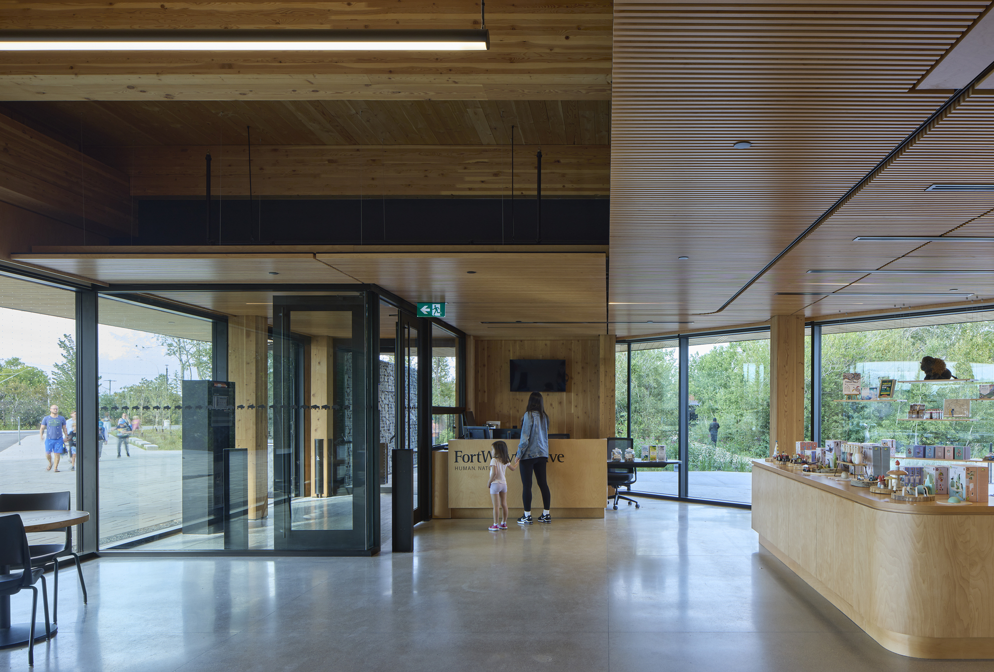 Entrance lobby with timber-clad ceiling and floor-to-ceiling glazing opening to parkland beyond