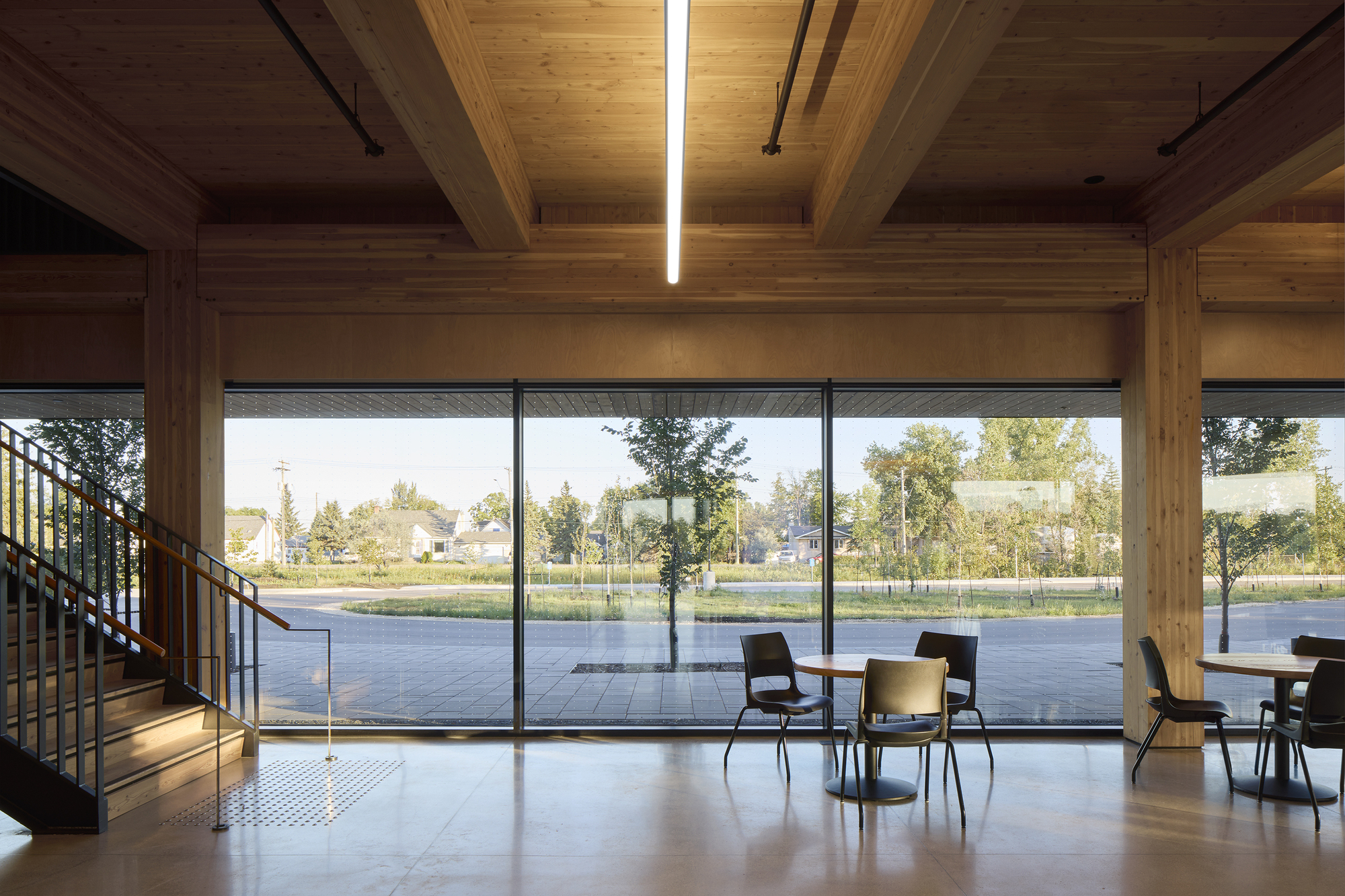 Mezzanine landing overlooking the glazed facade with exposed timber beams and linear skylights above